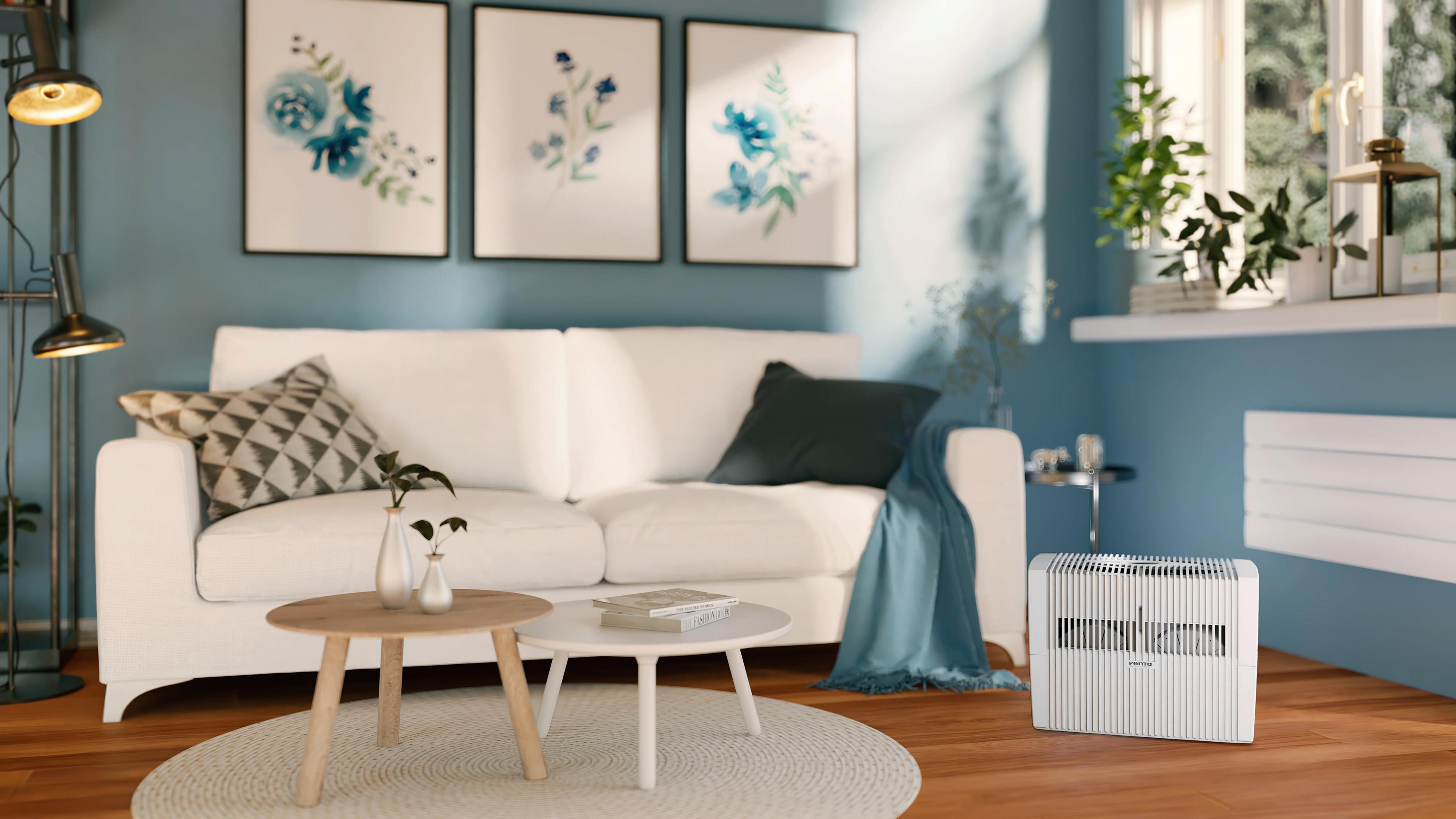 Living room with white sofa, blue wall, paintings, and side tables.