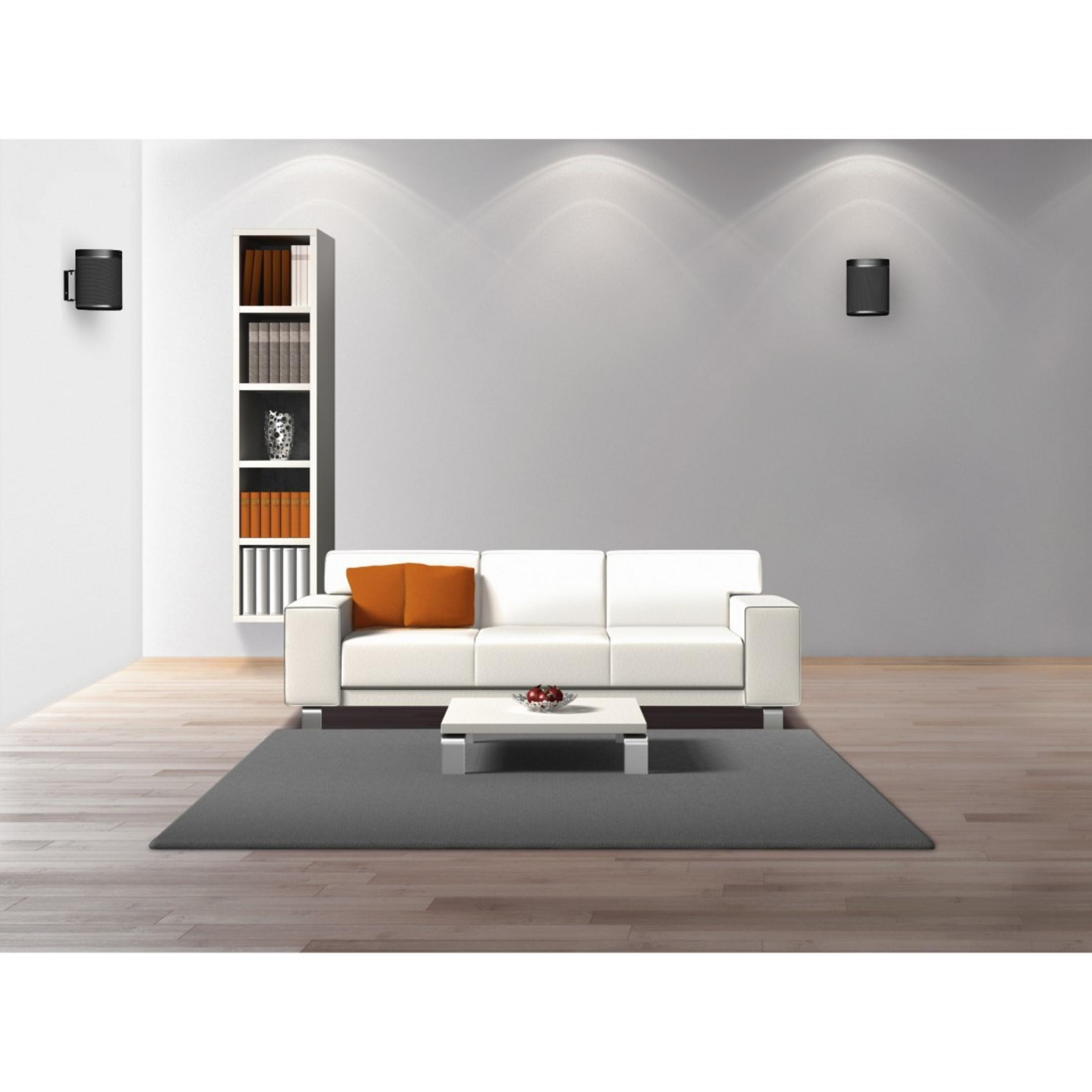 Ein Wohnzimmer mit weißem Sofa, grauem Teppich und Bücherregal.