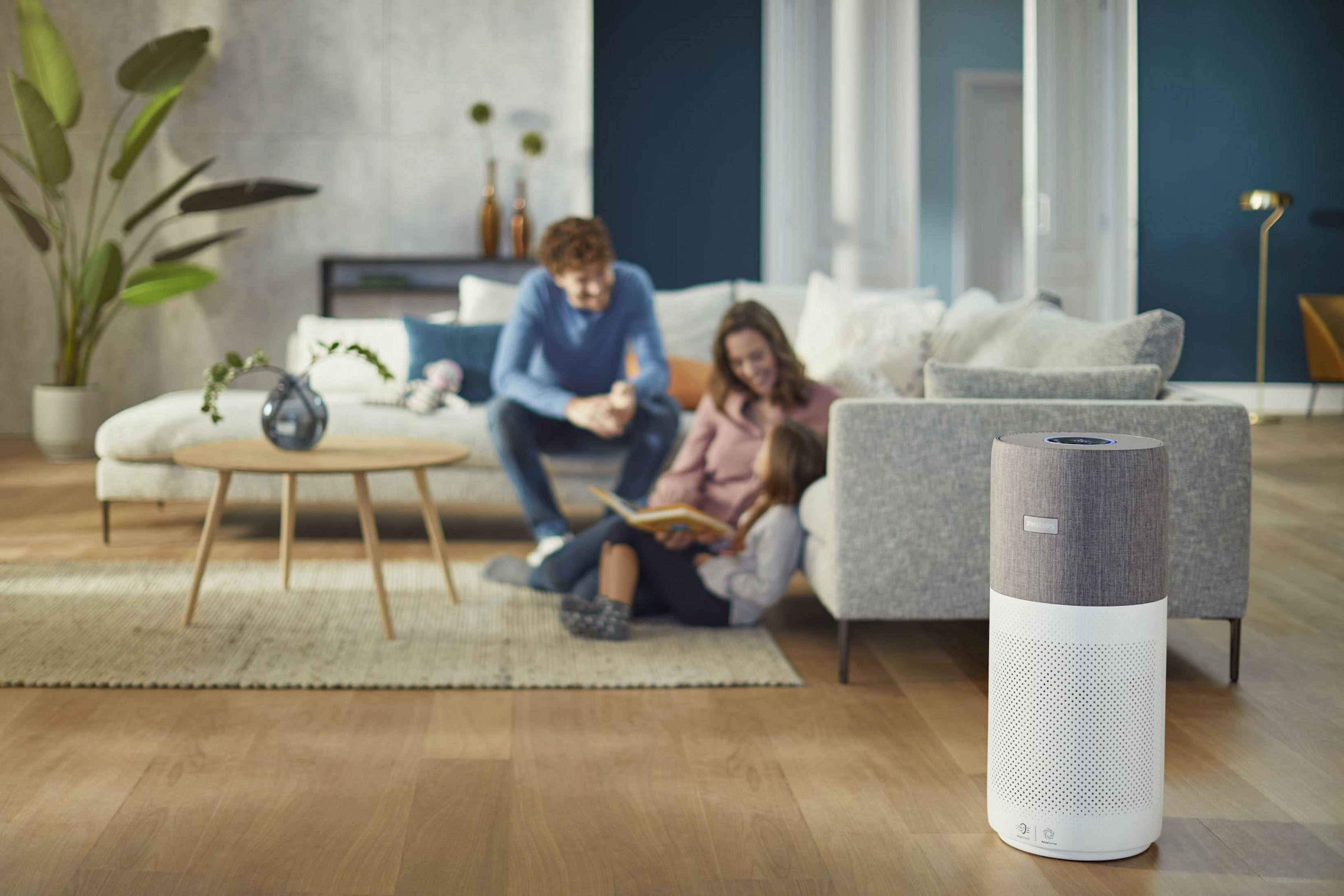 Una sala de estar con una familia y un purificador de aire en primer plano.