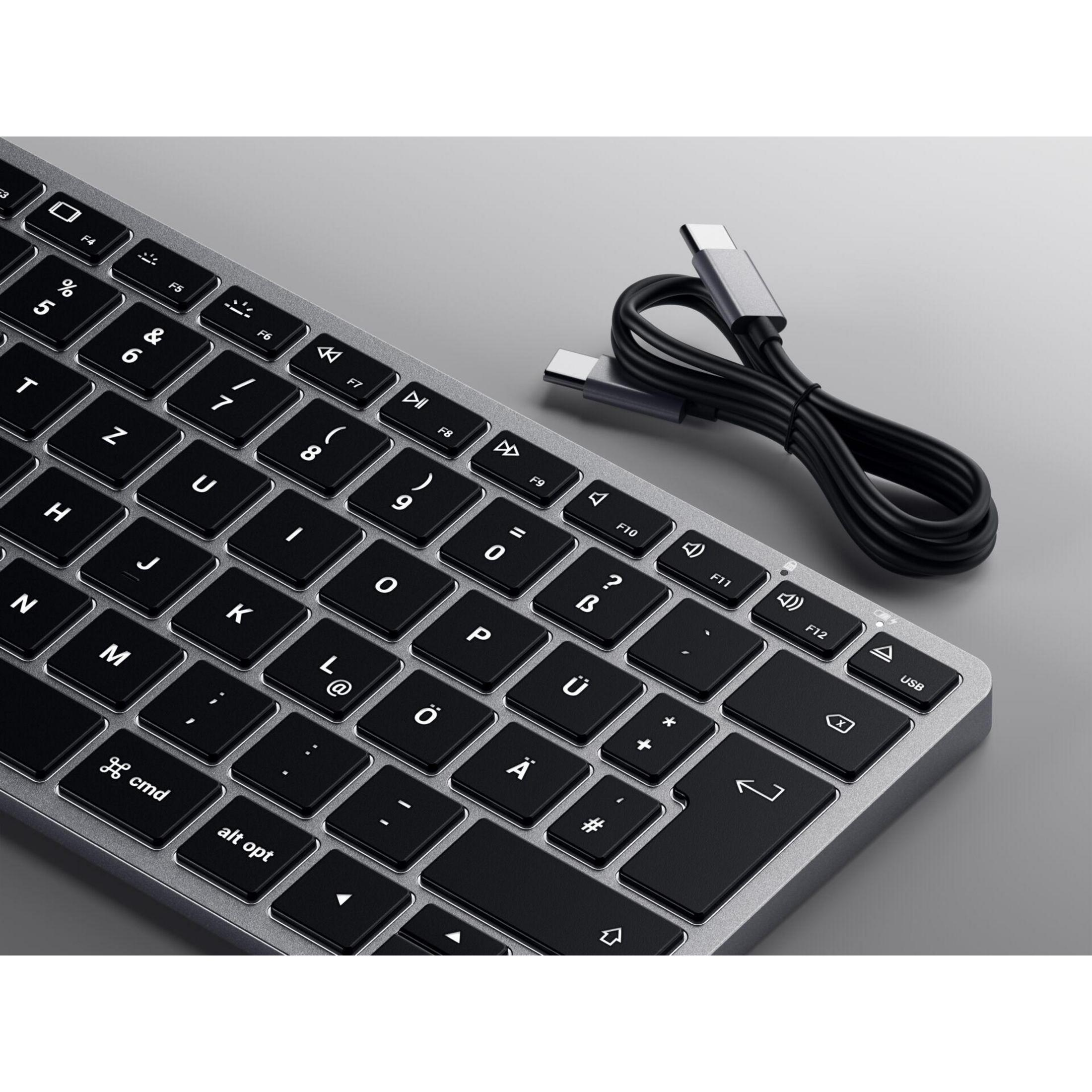 Silberne Tastatur mit schwarzen Tasten und USB-C-Kabel. Die Tastatur liegt auf grauem Untergrund.