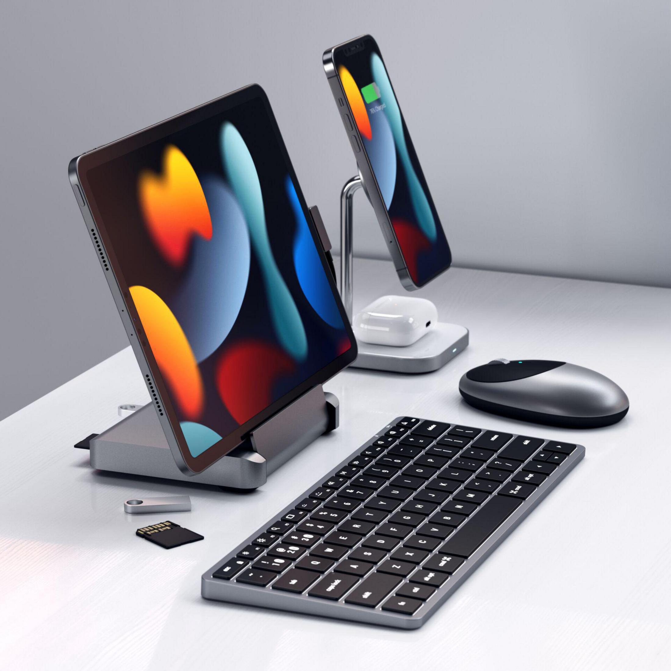 Ein Schreibtisch mit einem iPad, Smartphone, Tastatur, Maus und anderen technischen Geräten. Der Hintergrund ist weiß.