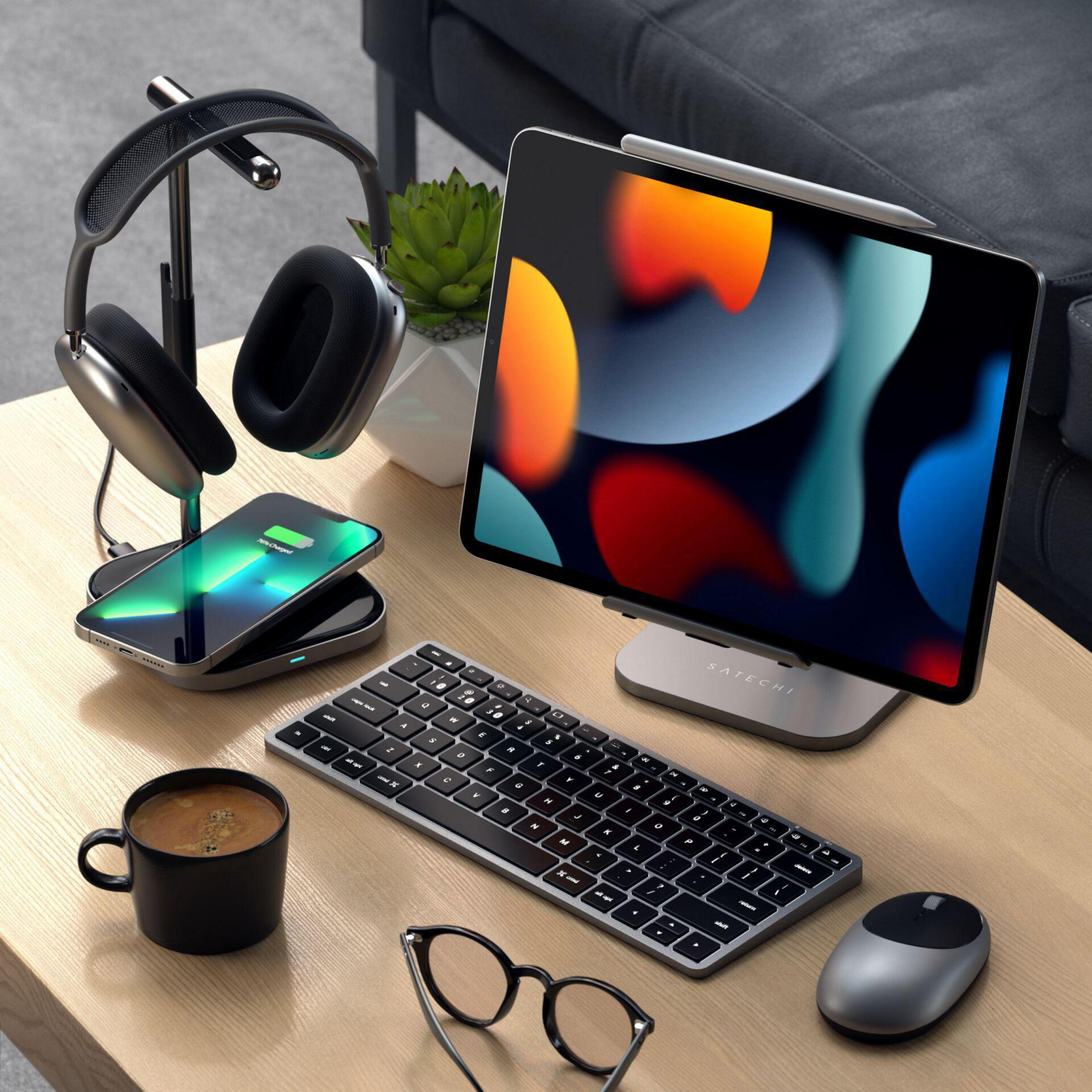 Ein Schreibtisch-Setup mit Tablet auf einem Ständer, Tastatur, Kopfhörern, Telefon und Kaffeetasse.