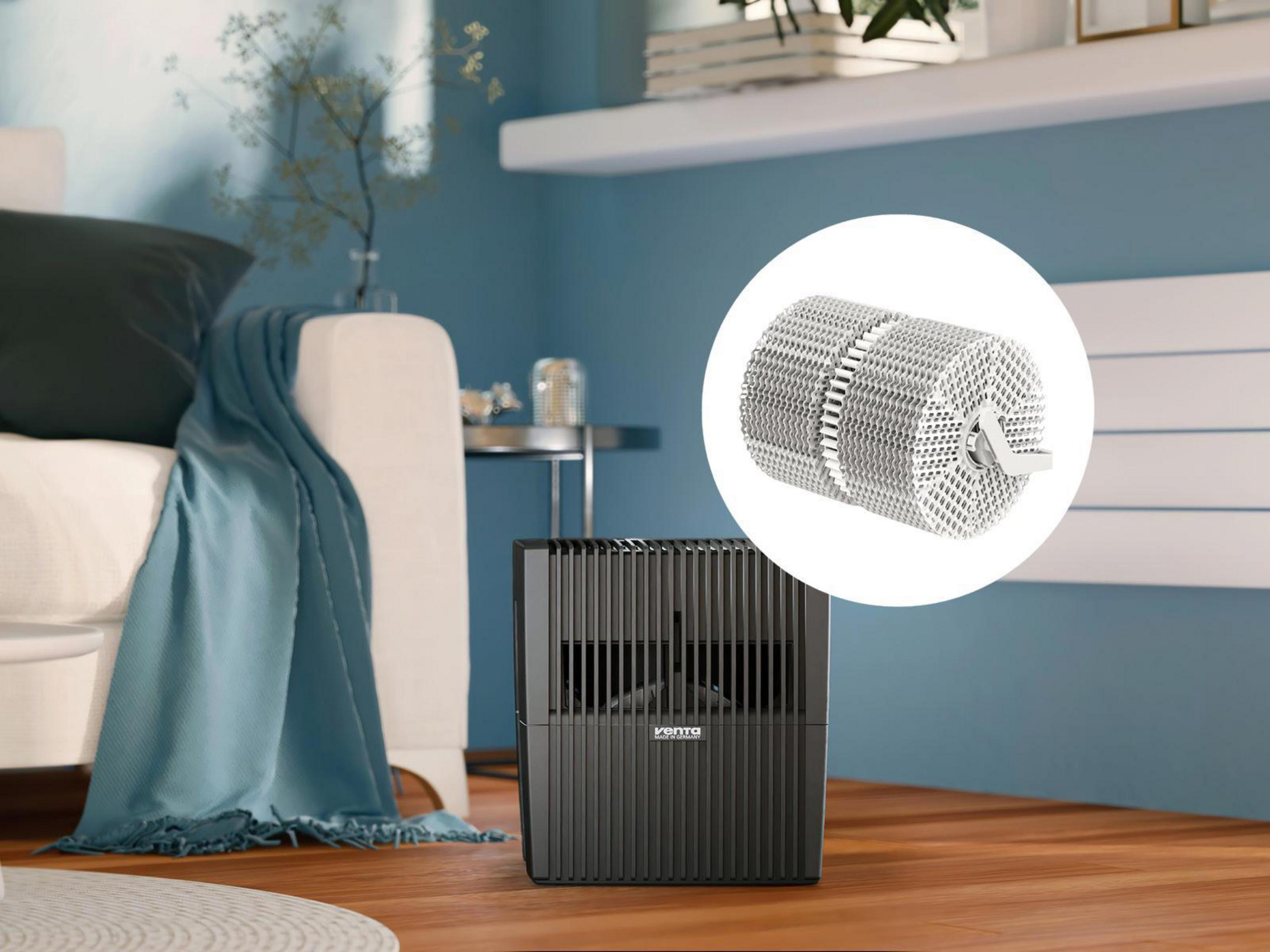 Czarny oczyszczacz powietrza i srebrny cylindryczny element. Tło przedstawia pokój.