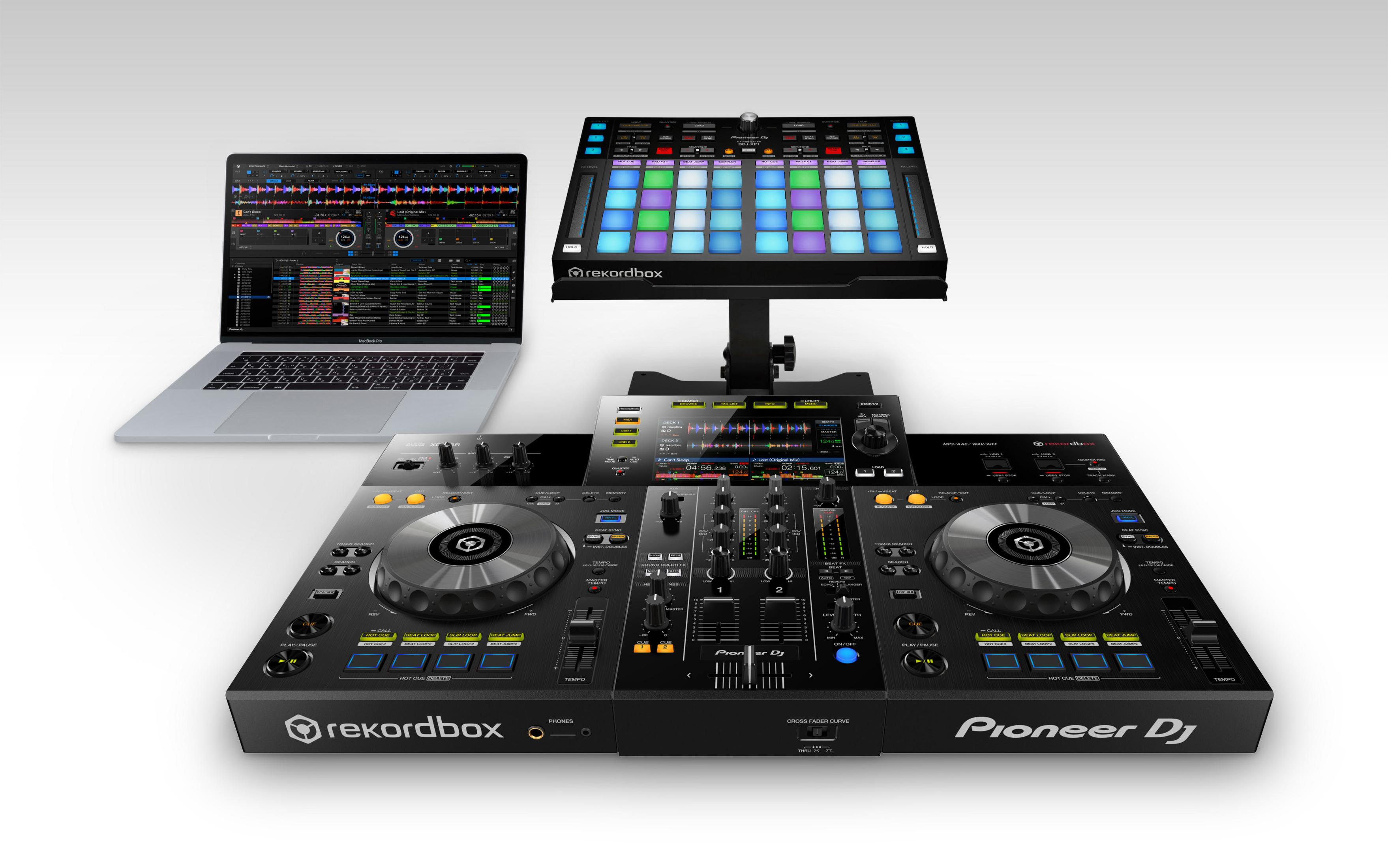 Configurazione DJ con laptop, controller e supporto. Colori nero e argento. Sfondo bianco.