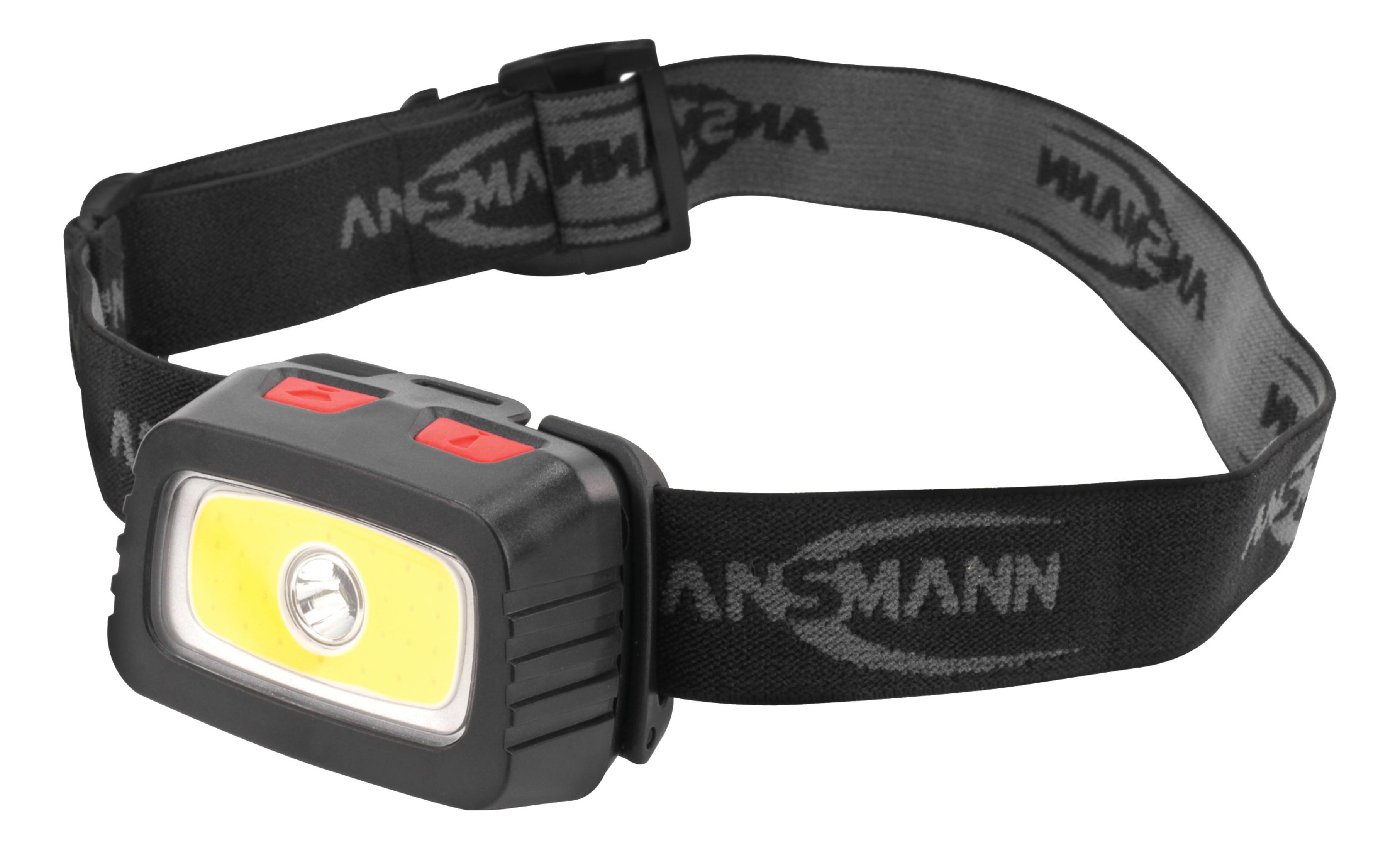 Schwarze Stirnlampe mit weißem Licht. Das Band ist schwarz und grau, mit dem Markennamen ANSMANN.