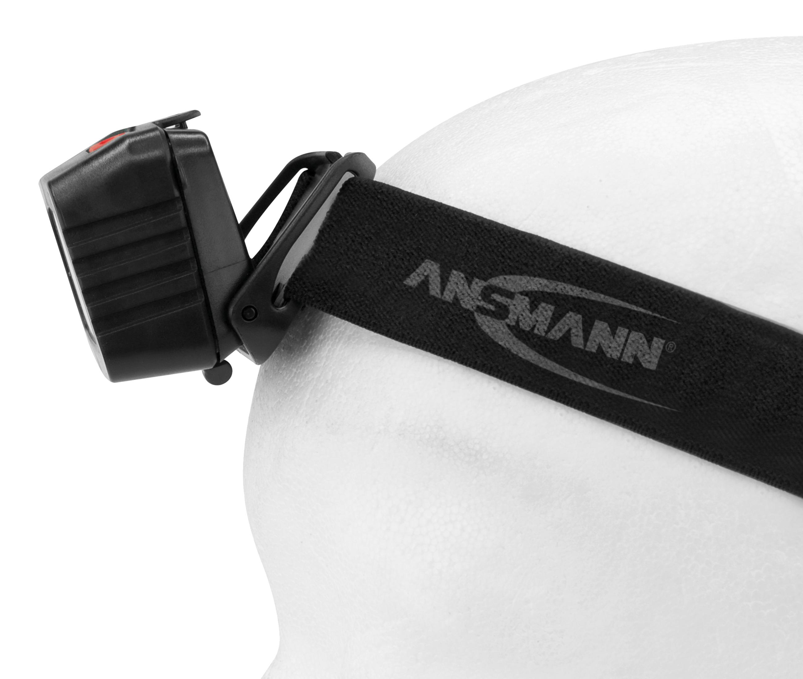 Schwarze Stirnlampe auf weißer Kopf-Form, mit schwarzem Gurt.