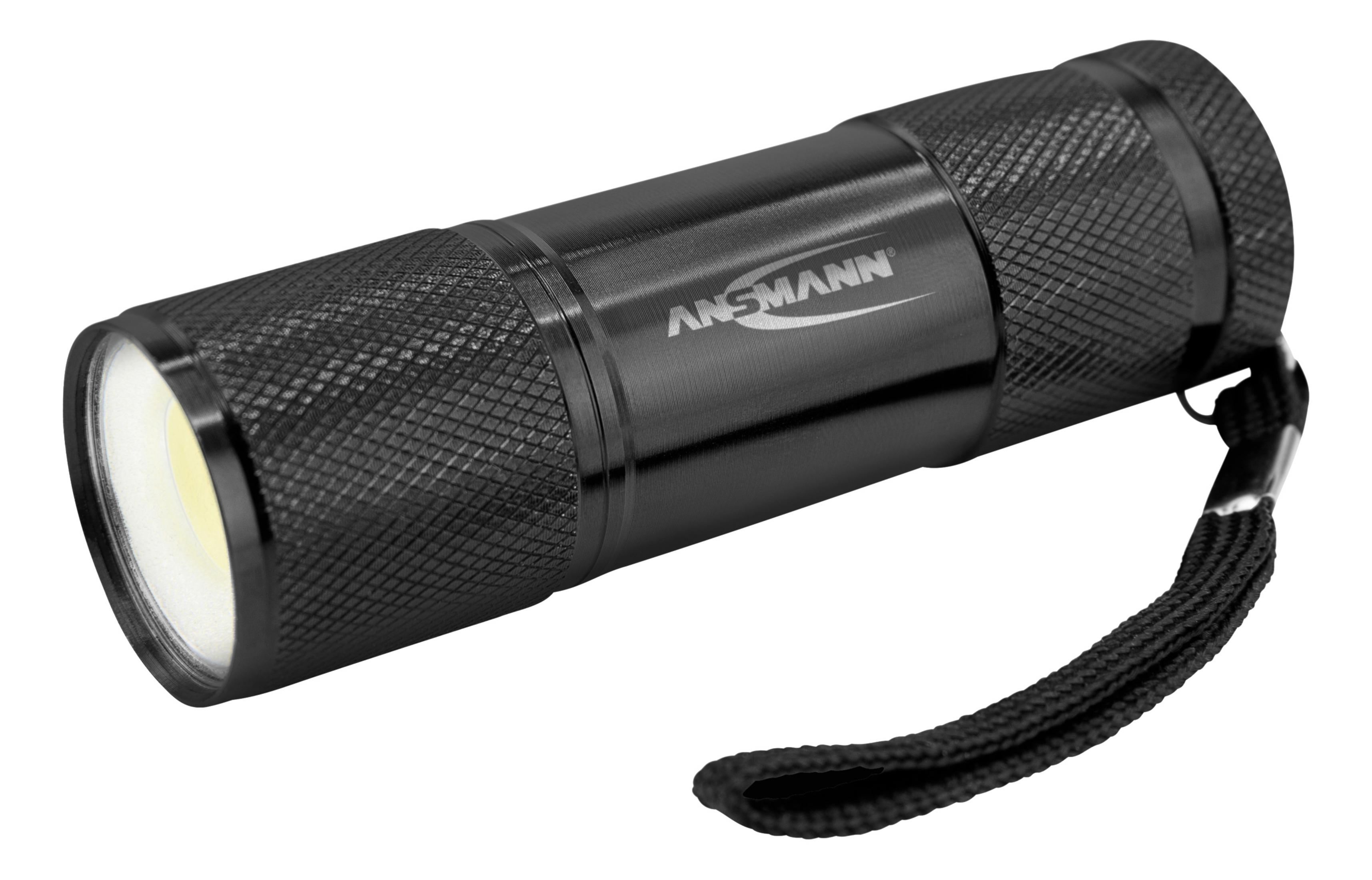 Schwarze Taschenlampe mit schwarzer Handschlaufe. Die Taschenlampe befindet sich auf weißem Hintergrund und ist angewinkelt.