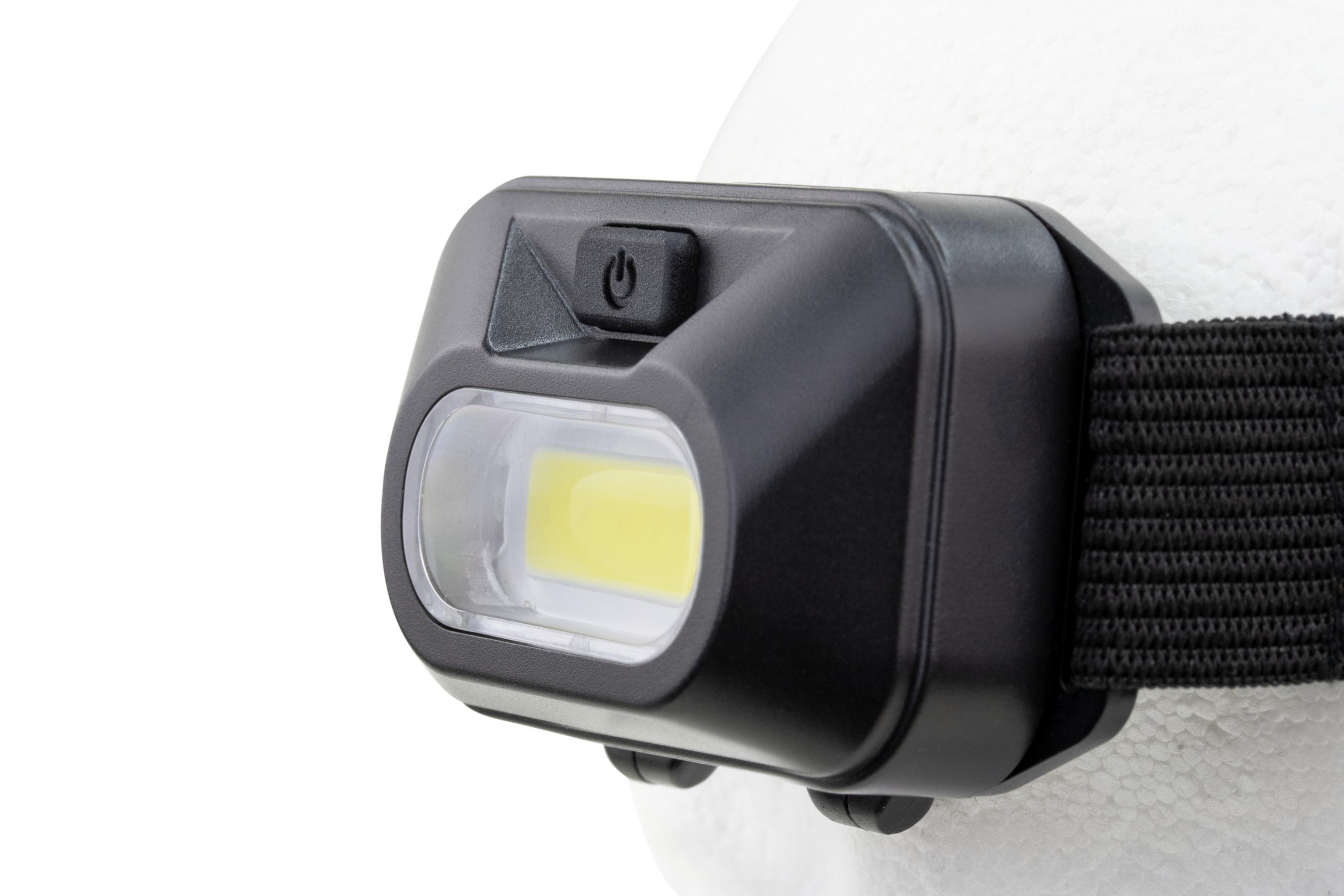 Eine schwarze Stirnlampe, befestigt an einer weißen Oberfläche. Sie hat ein Licht und einen Ein-/Ausschalter.