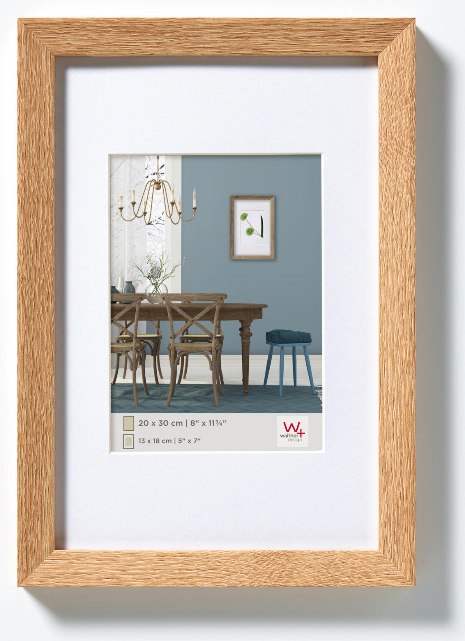 Ein Holzbilderrahmen mit weißem Passepartout, der ein gerahmtes Bild an einer blauen Wand zeigt.