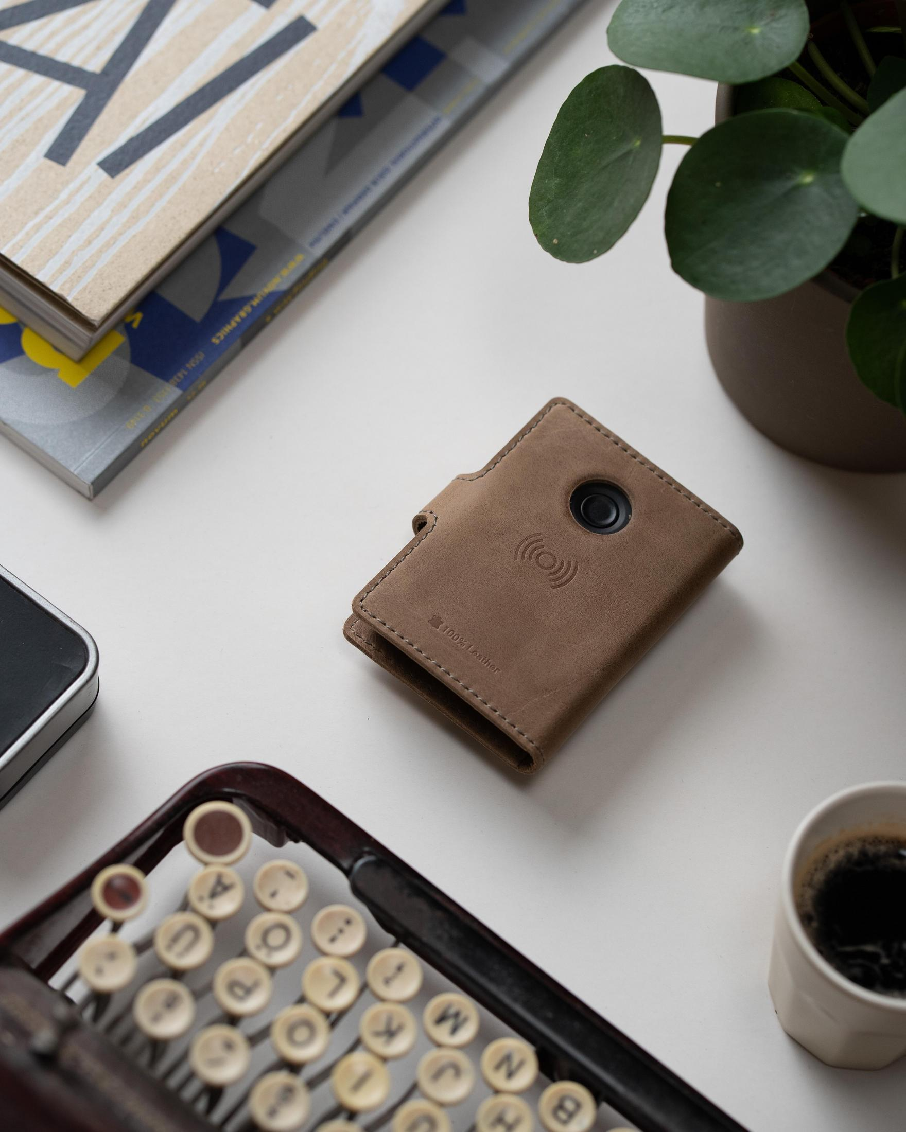 Eine braune Ledergeldbörse auf einem weißen Schreibtisch mit Tastatur und Kaffeetasse.