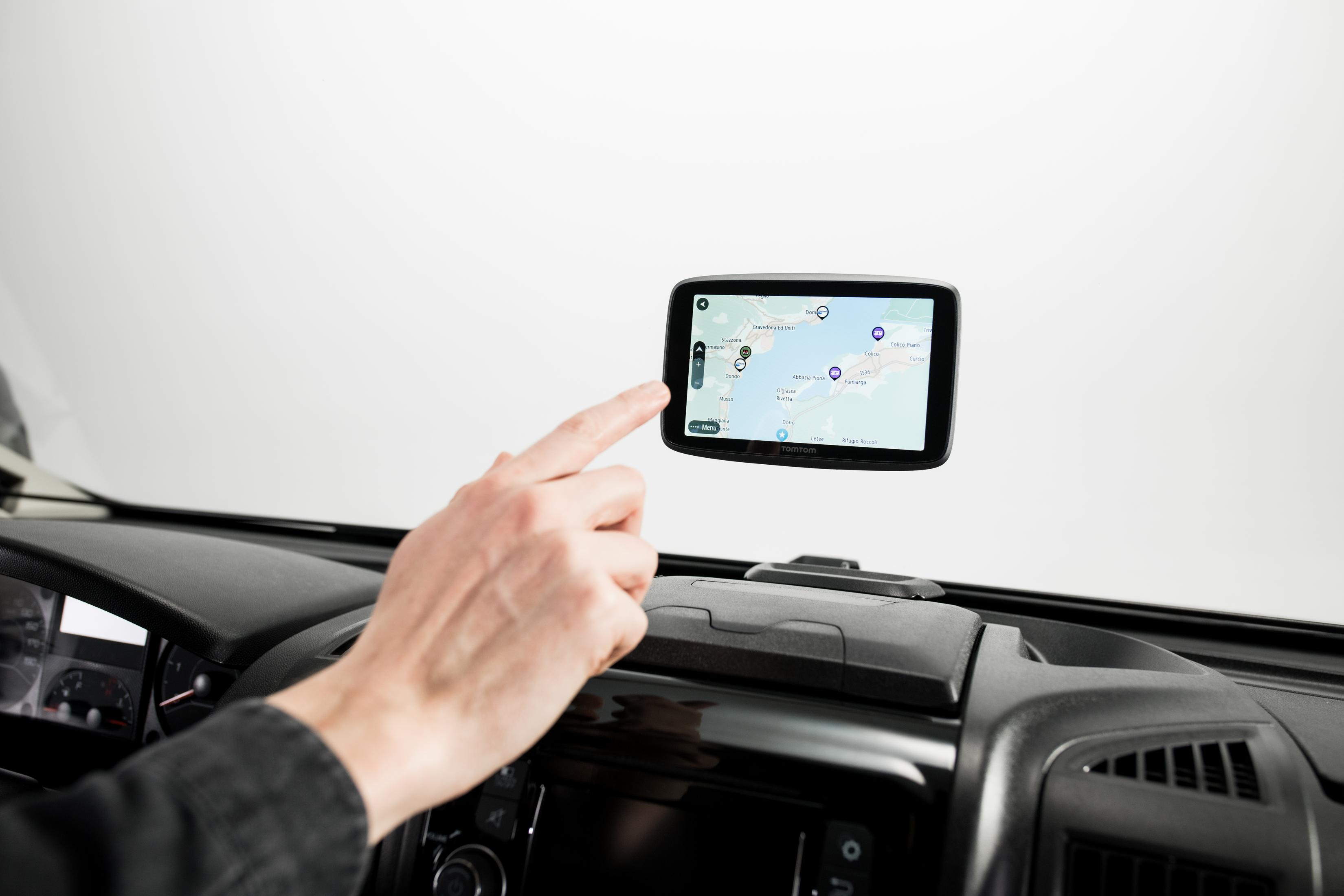 Die Hand einer Person berührt einen Navigationsbildschirm in einem Auto, der eine Karte anzeigt.