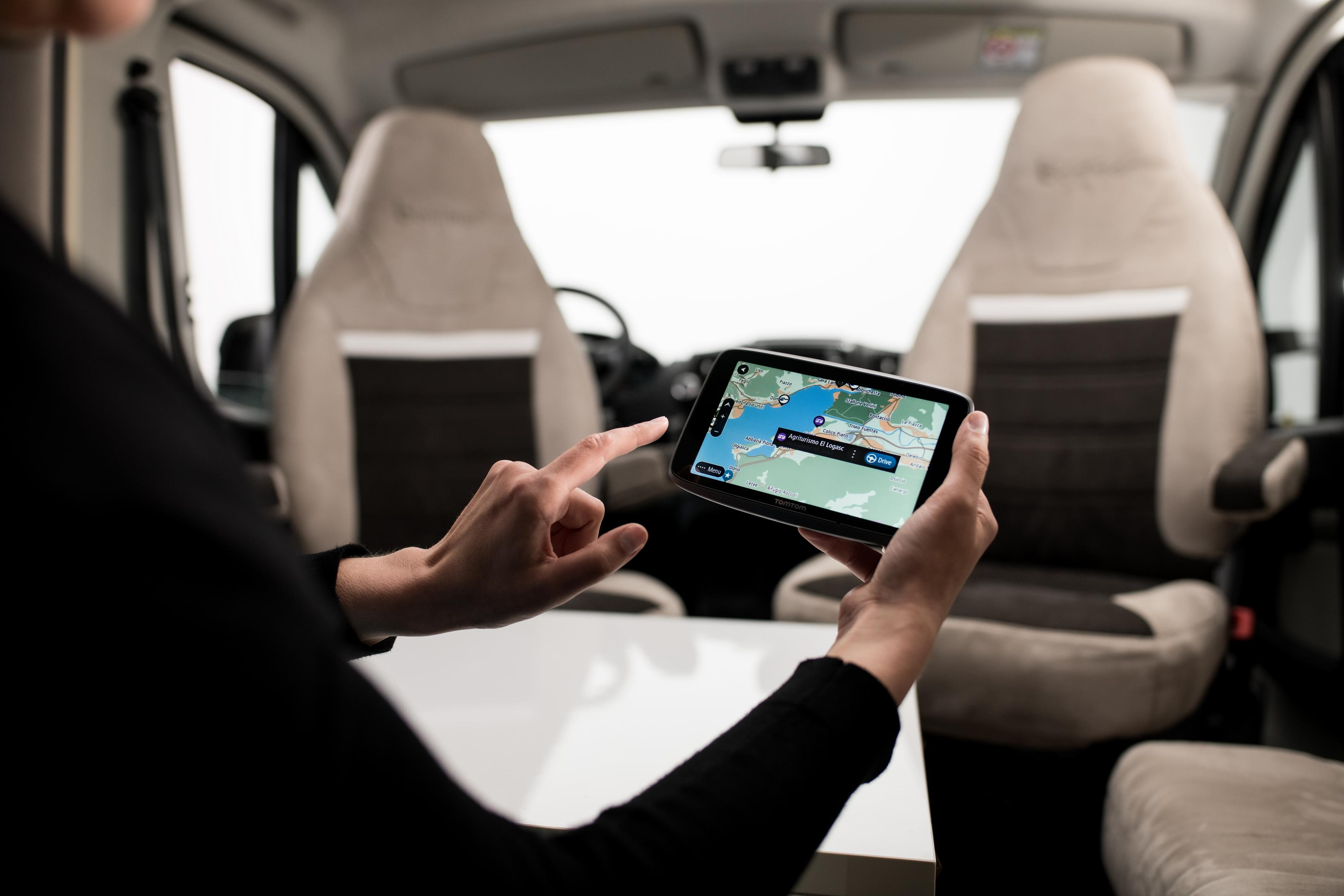 Eine Person benutzt ein Tablet mit einer Karte in einem Fahrzeug.