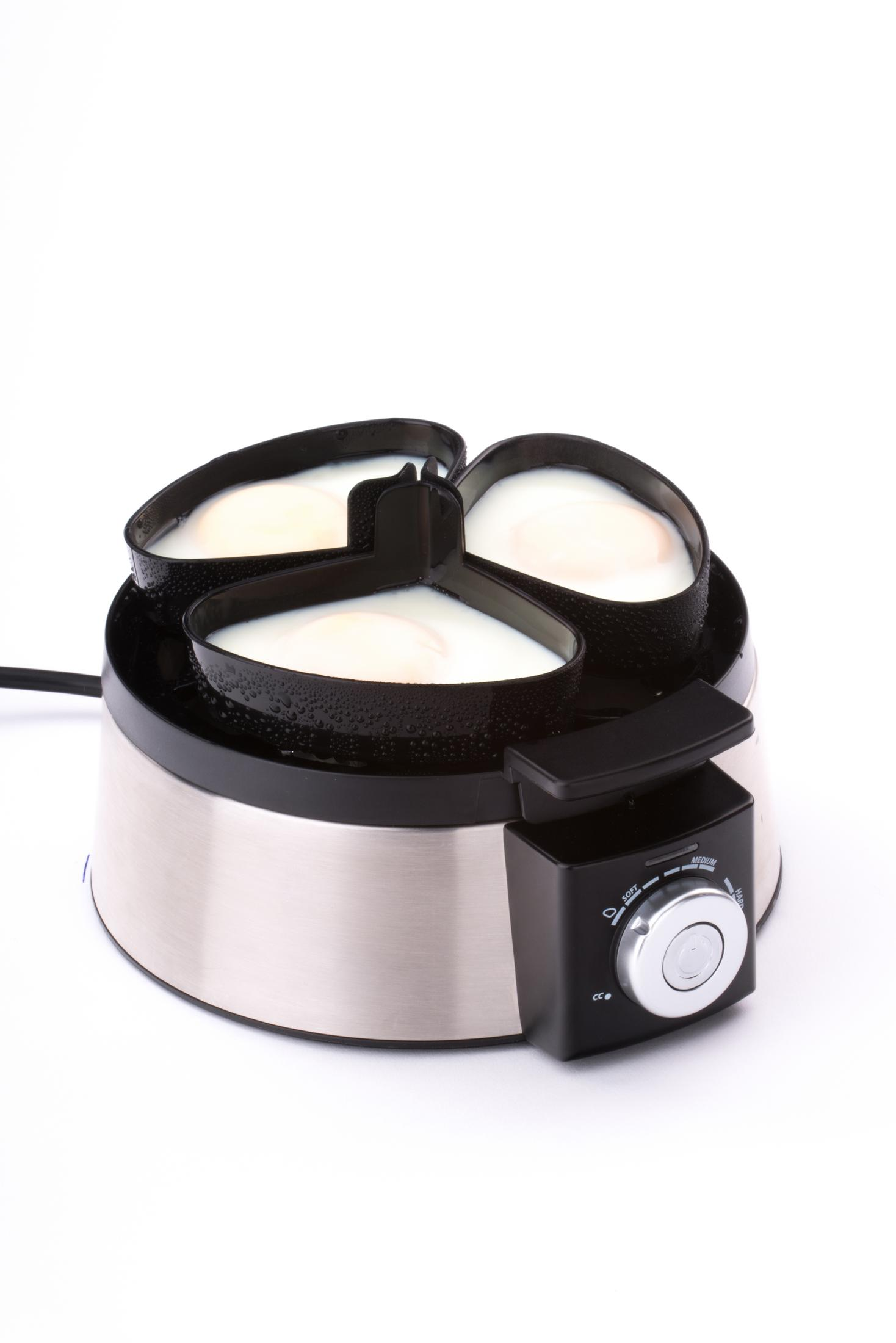 Urządzenie do gotowania jajek z trzema foremkami w kształcie serca zawierającymi ugotowane jajka. Ma pokrętło sterowania.