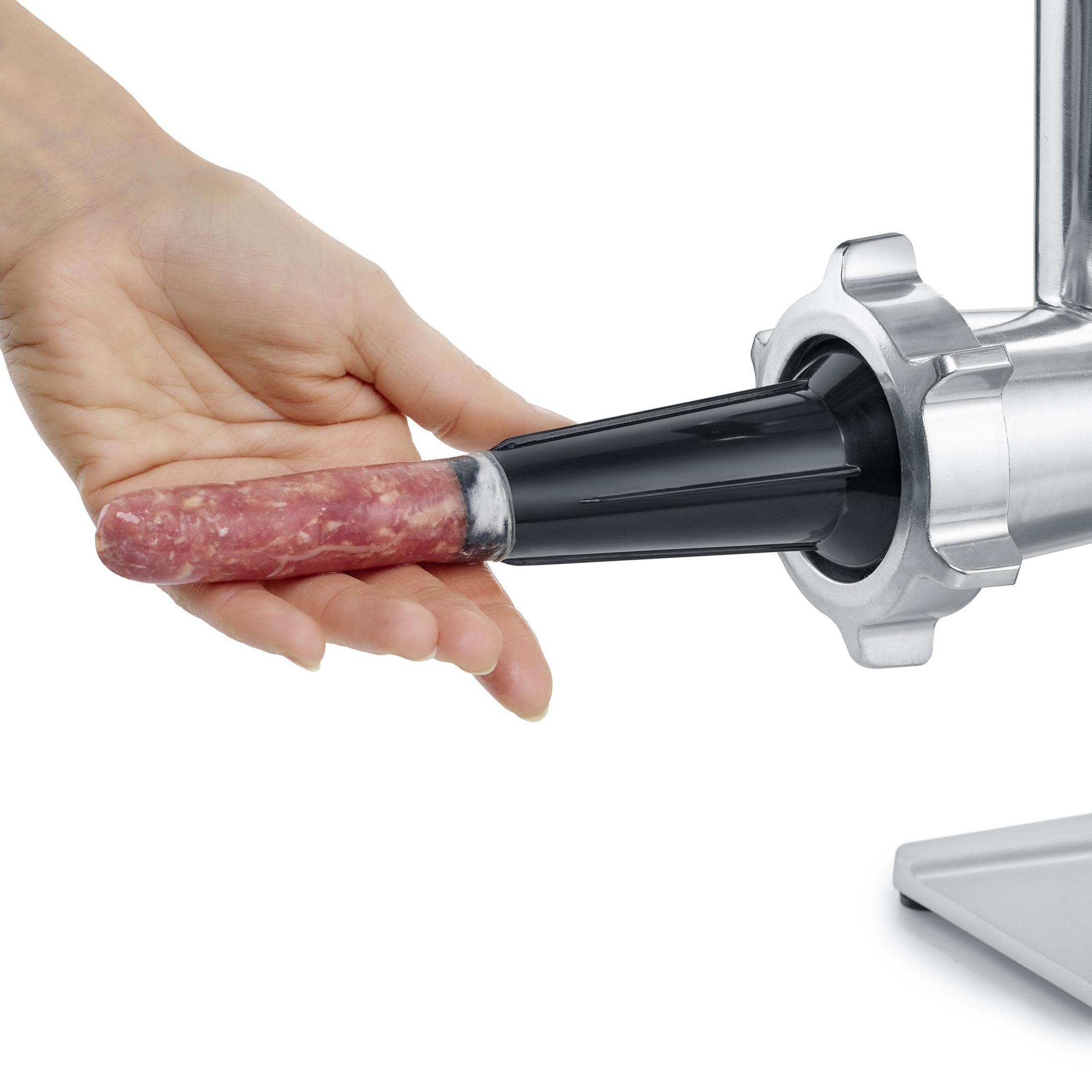 Ręka trzymająca kiełbasę wpycha ją do maszynki do mięsa, ze stali nierdzewnej. Białe tło.