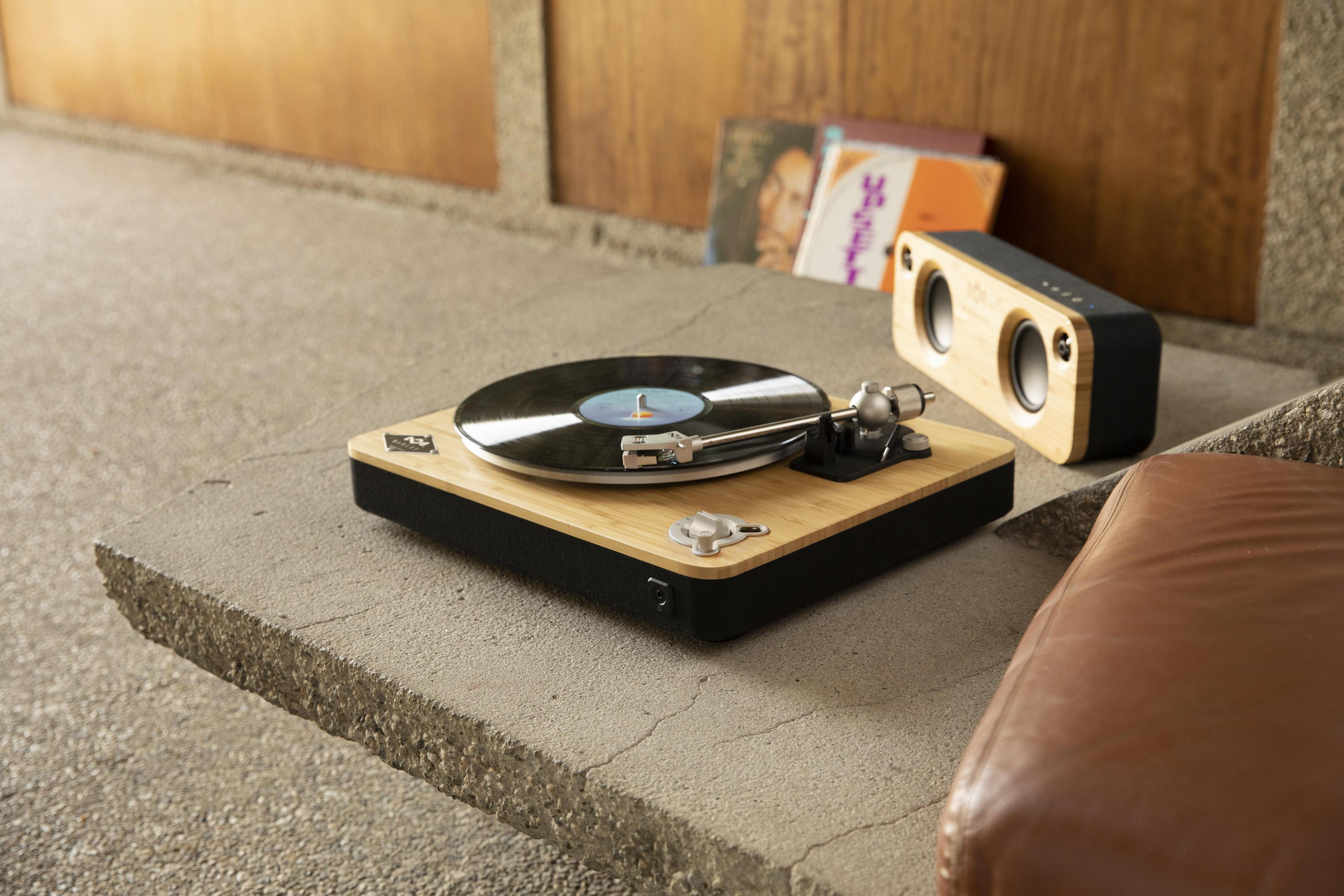 Platine vinyle avec un disque. Enceintes et canapé marron en arrière-plan.