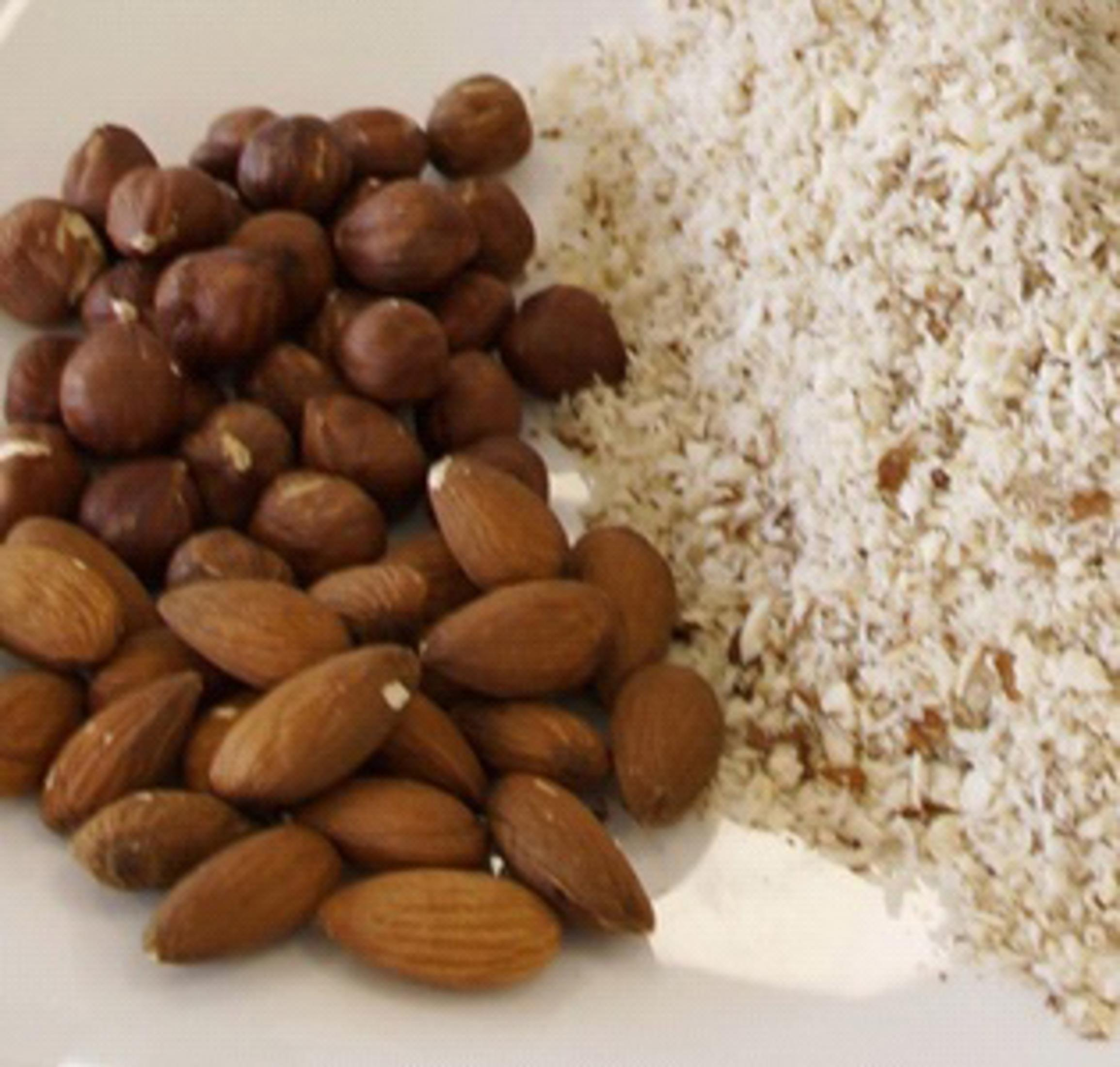 Noisettes, amandes et farine d'amandes sur une surface blanche, gros plan.