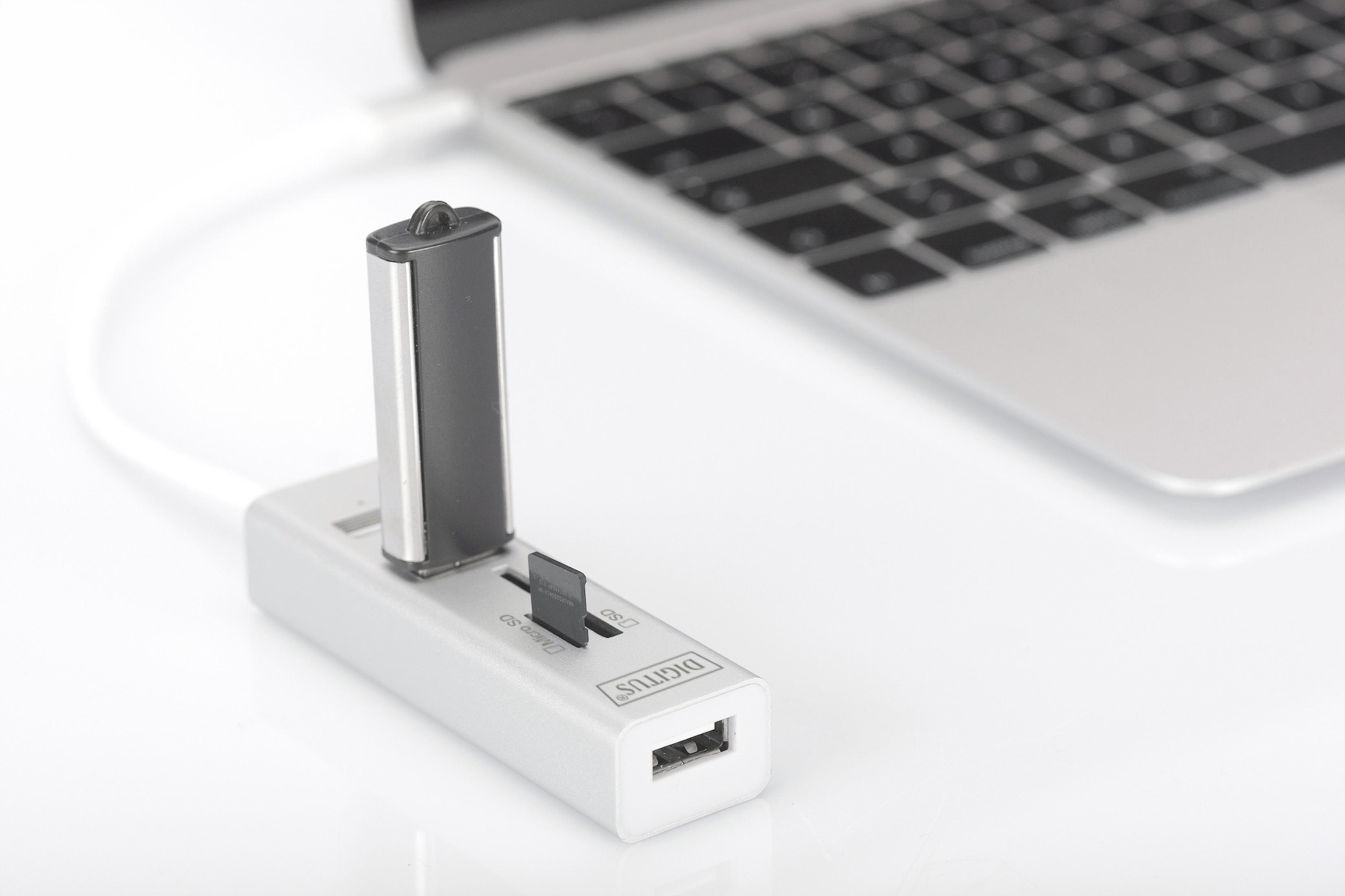 Hub USB z pendrivem i kartą SD, podłączony do laptopa. Biała powierzchnia.