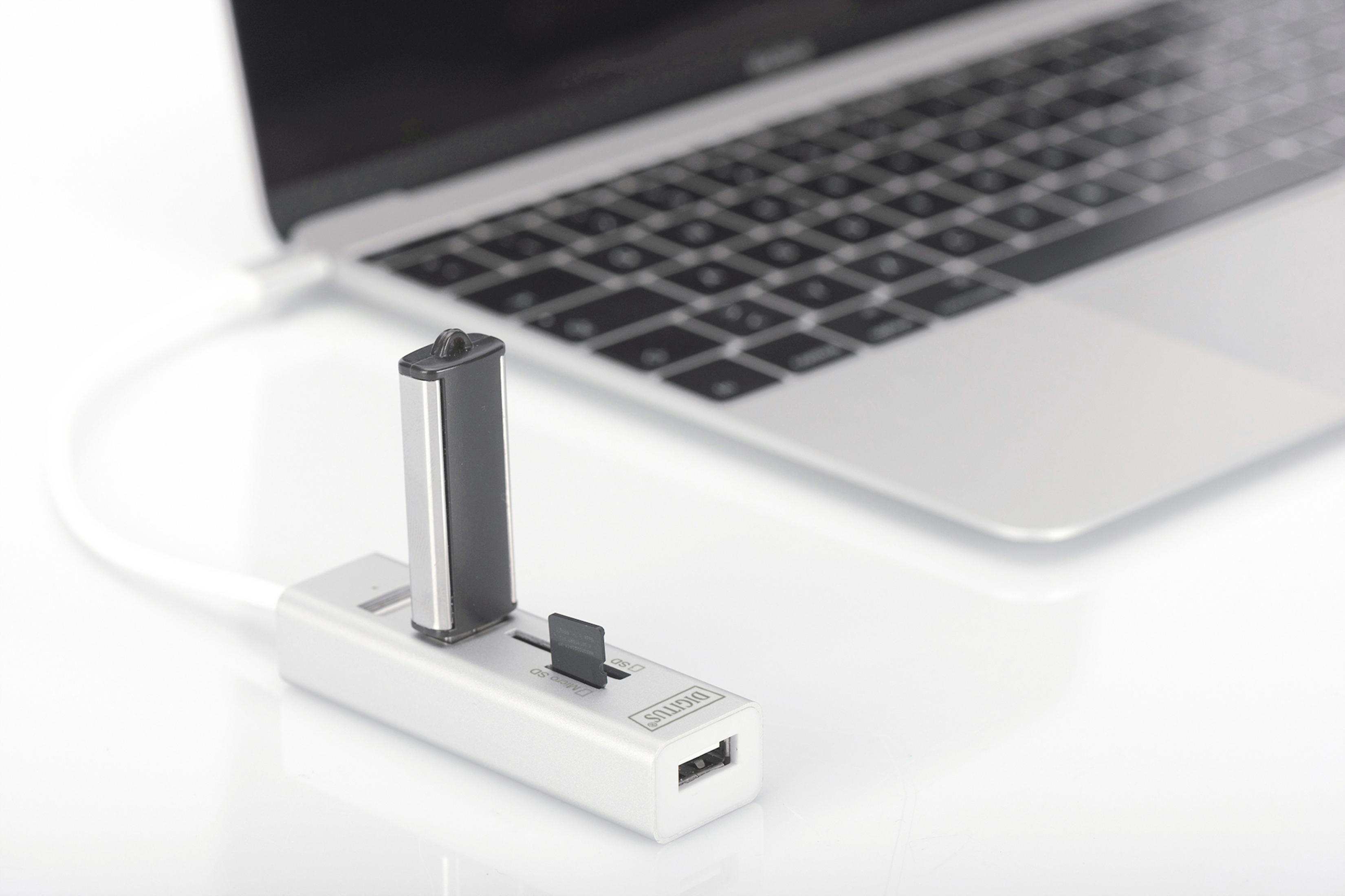 Srebrny hub USB z pendrivem i czytnikiem kart podłączonym do laptopa.