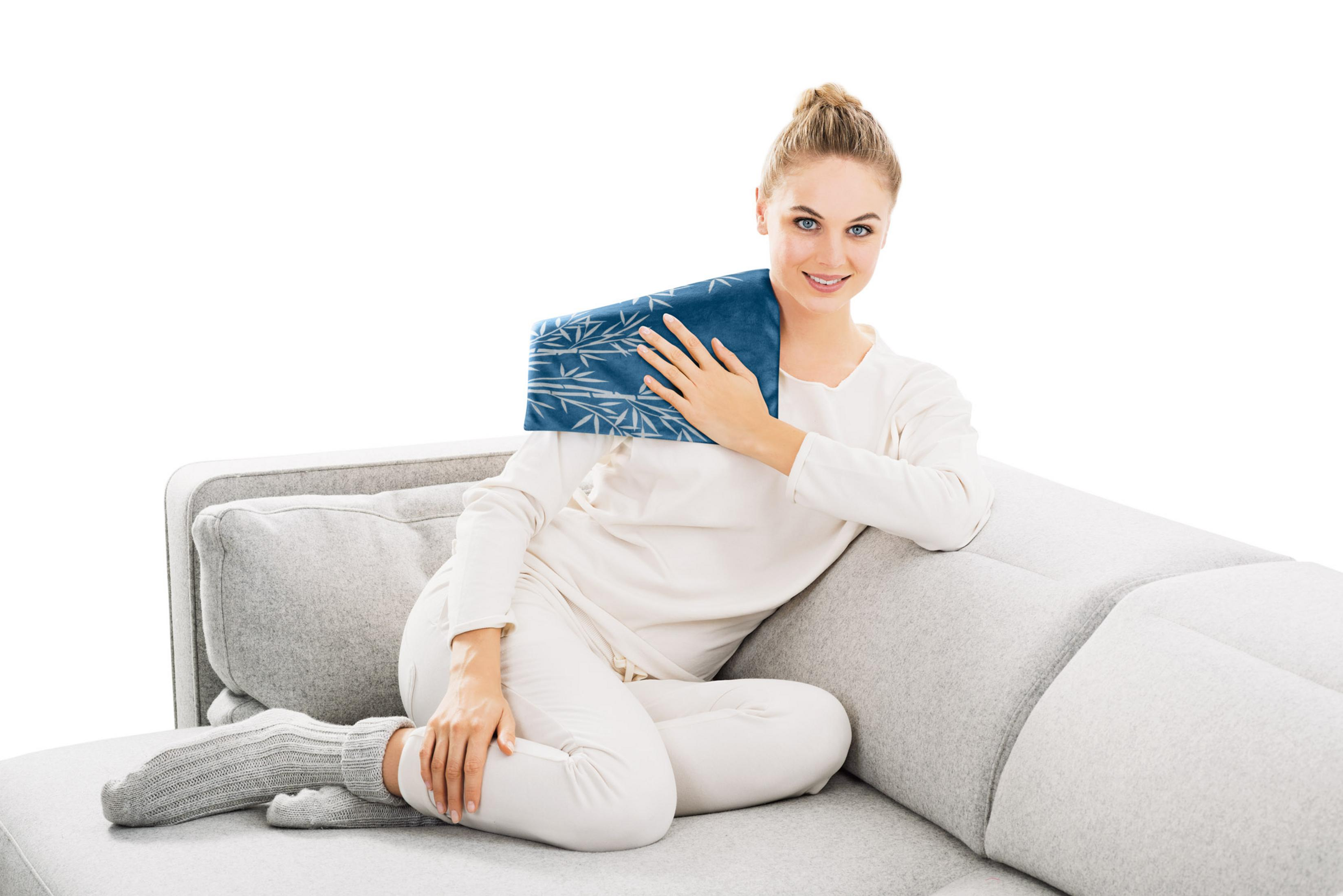 Donna bionda su un divano grigio che tiene una borsa termica blu a fantasia sulla spalla.