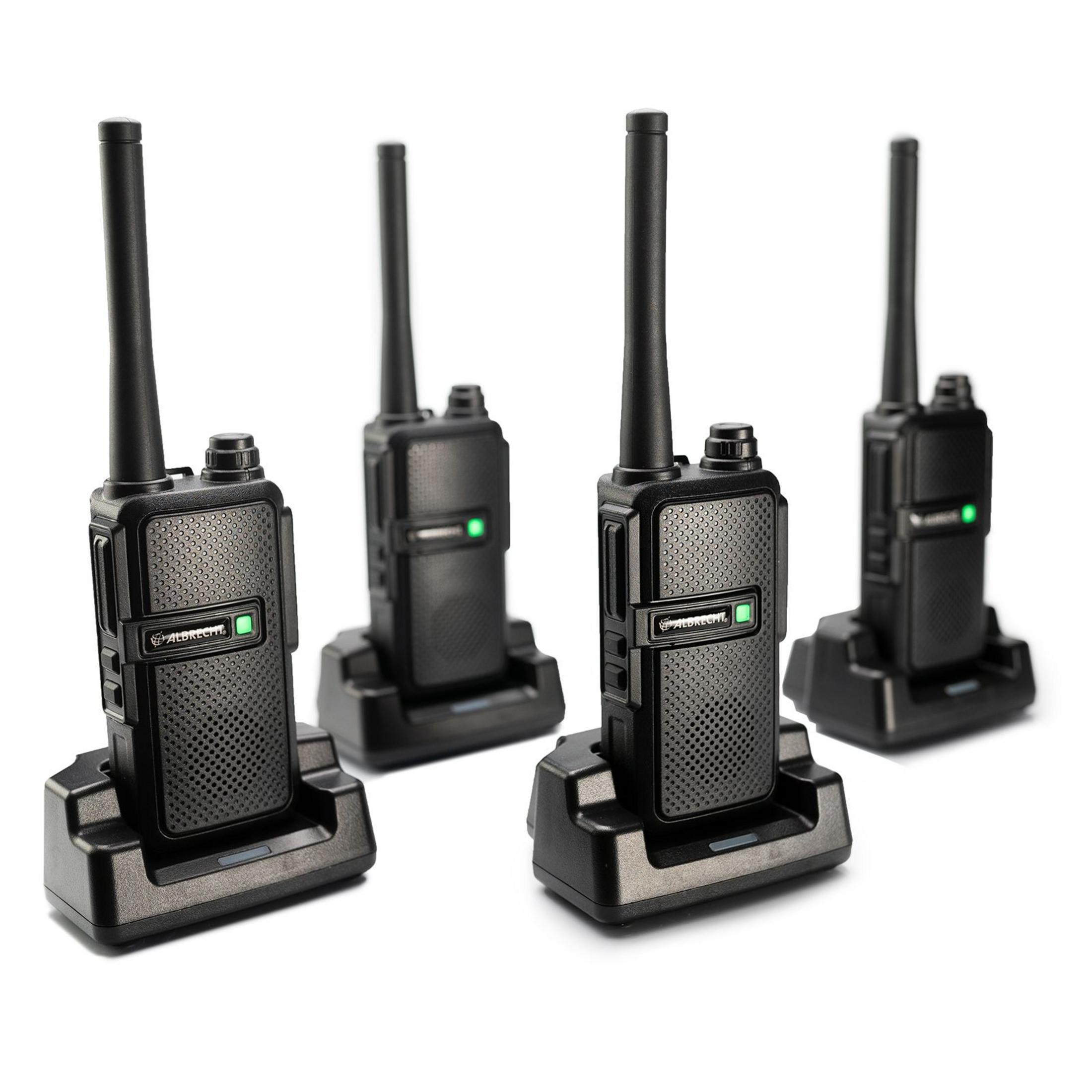 Vier schwarze Walkie-Talkies in Ladestationen. Jedes hat eine Antenne und eine grüne Kontrollleuchte.
