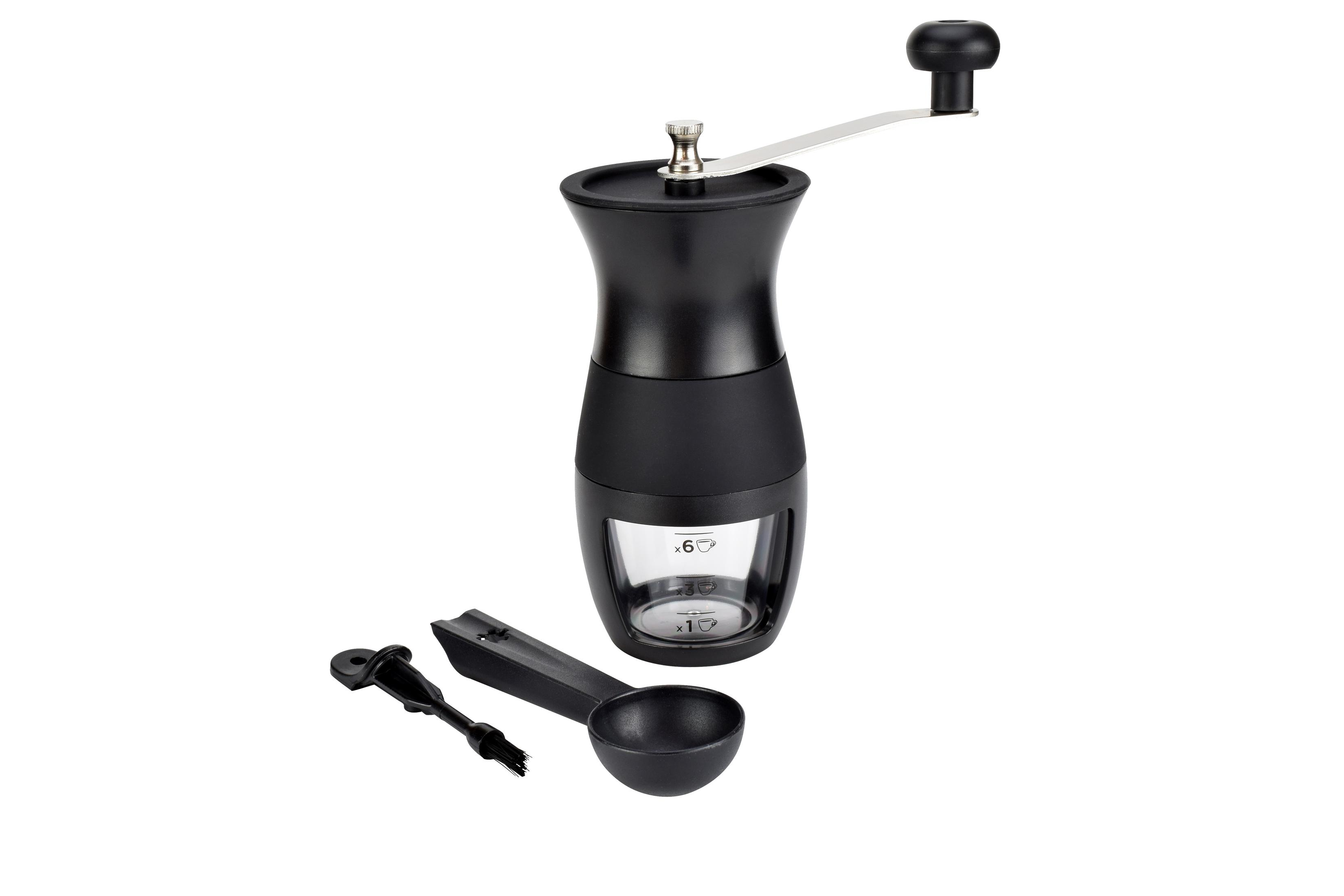 Schwarze manuelle Kaffeemühle mit Glasbehälter, Löffel und Reinigungsbürste auf weißer Oberfläche.
