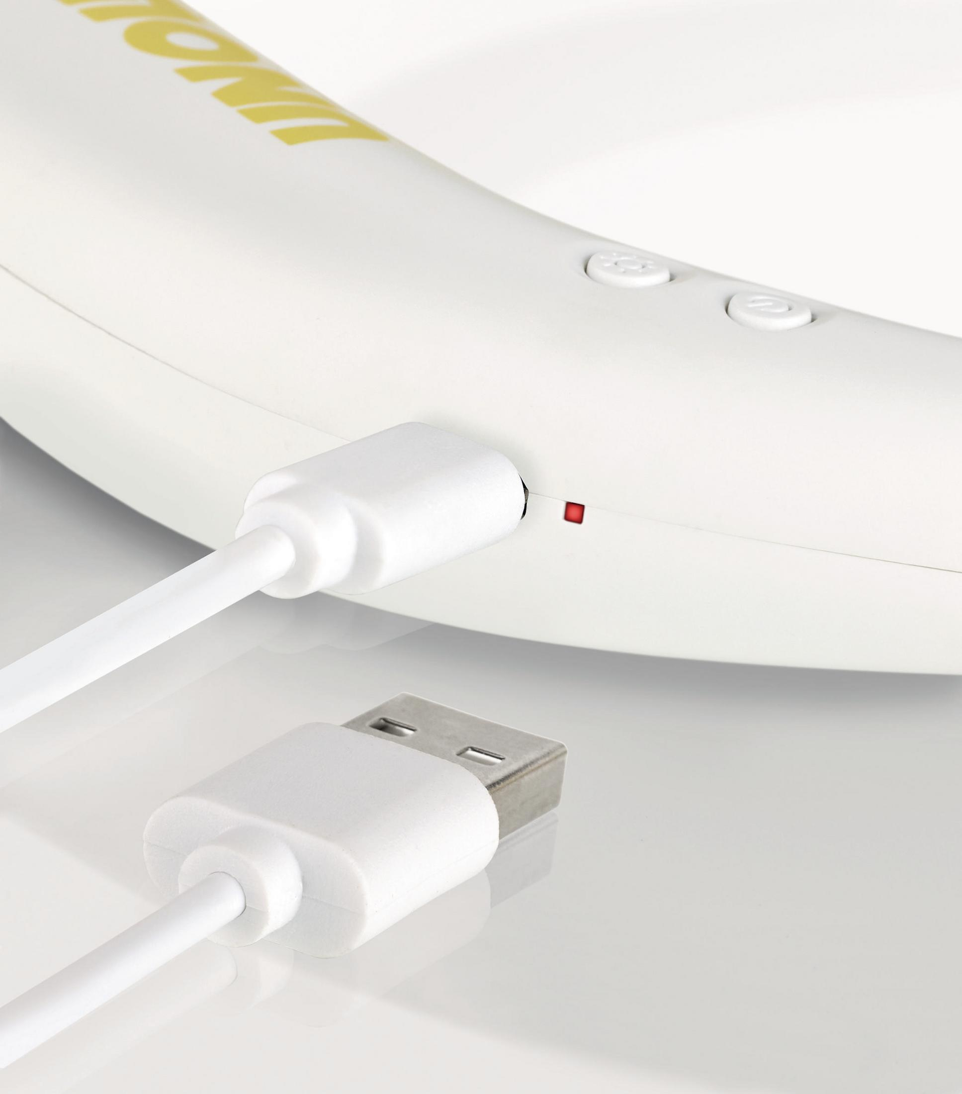 Białe urządzenie ładowane białym kablem. Kabel ma USB i złącze.