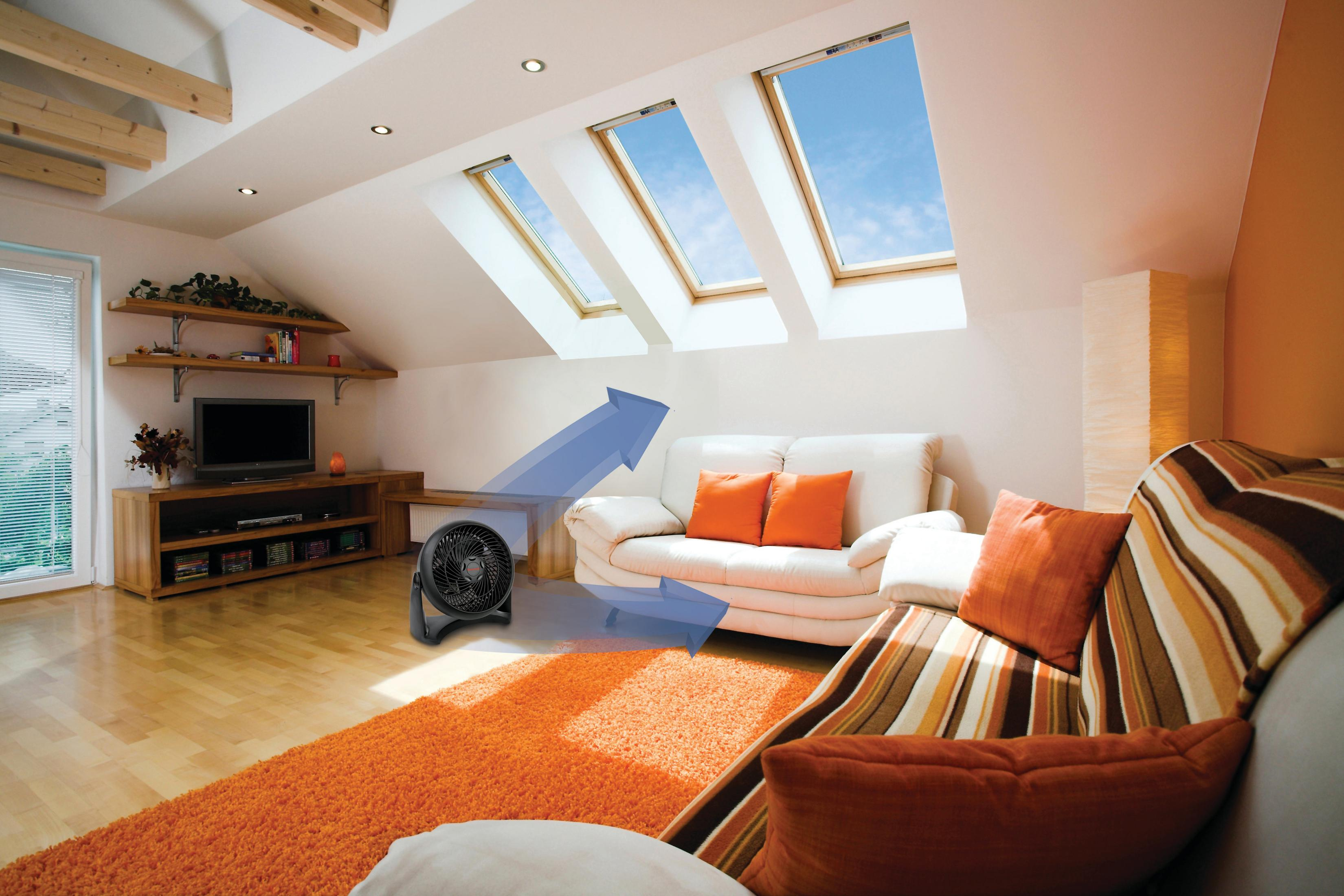 Salon z czarnym wentylatorem kierującym powietrze w stronę białej kanapy.