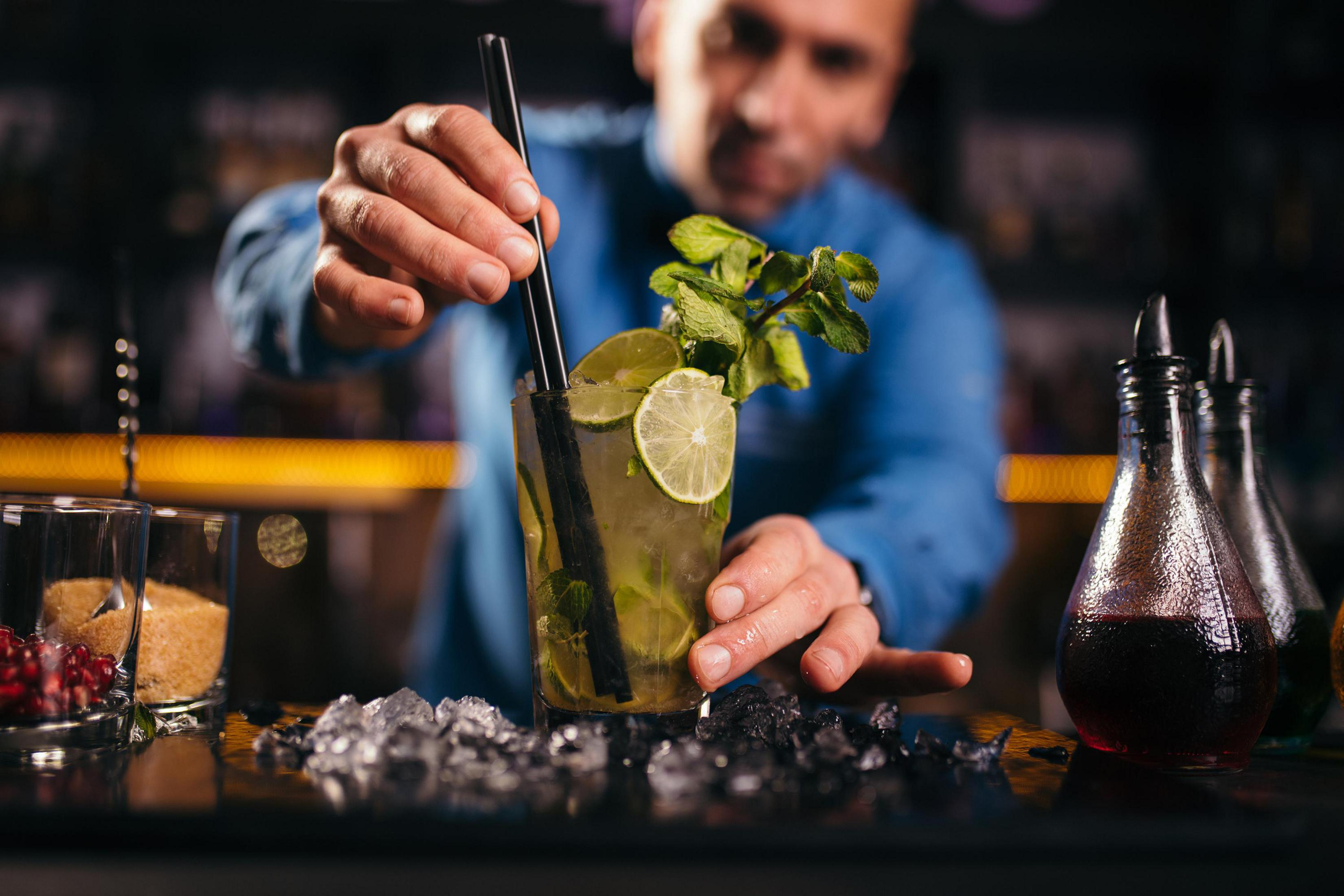 Ein Barkeeper bereitet einen Cocktail mit Limette und Minze mit Eis zu.