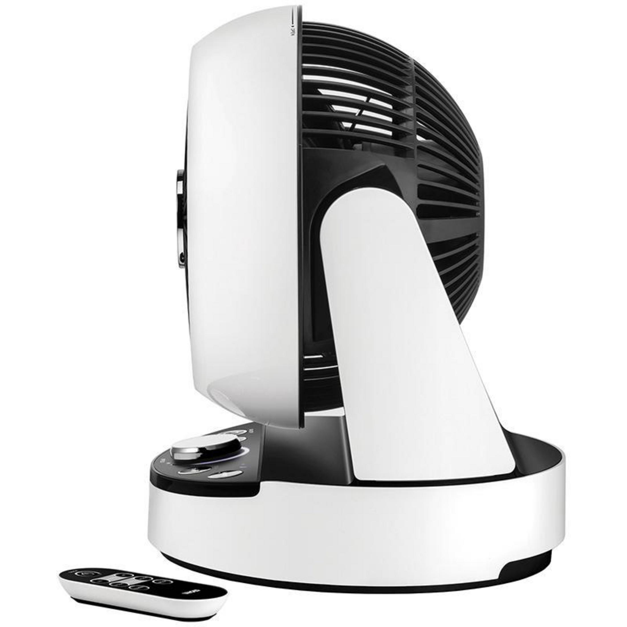 Ventilador blanco y negro con mando a distancia sobre una superficie blanca.