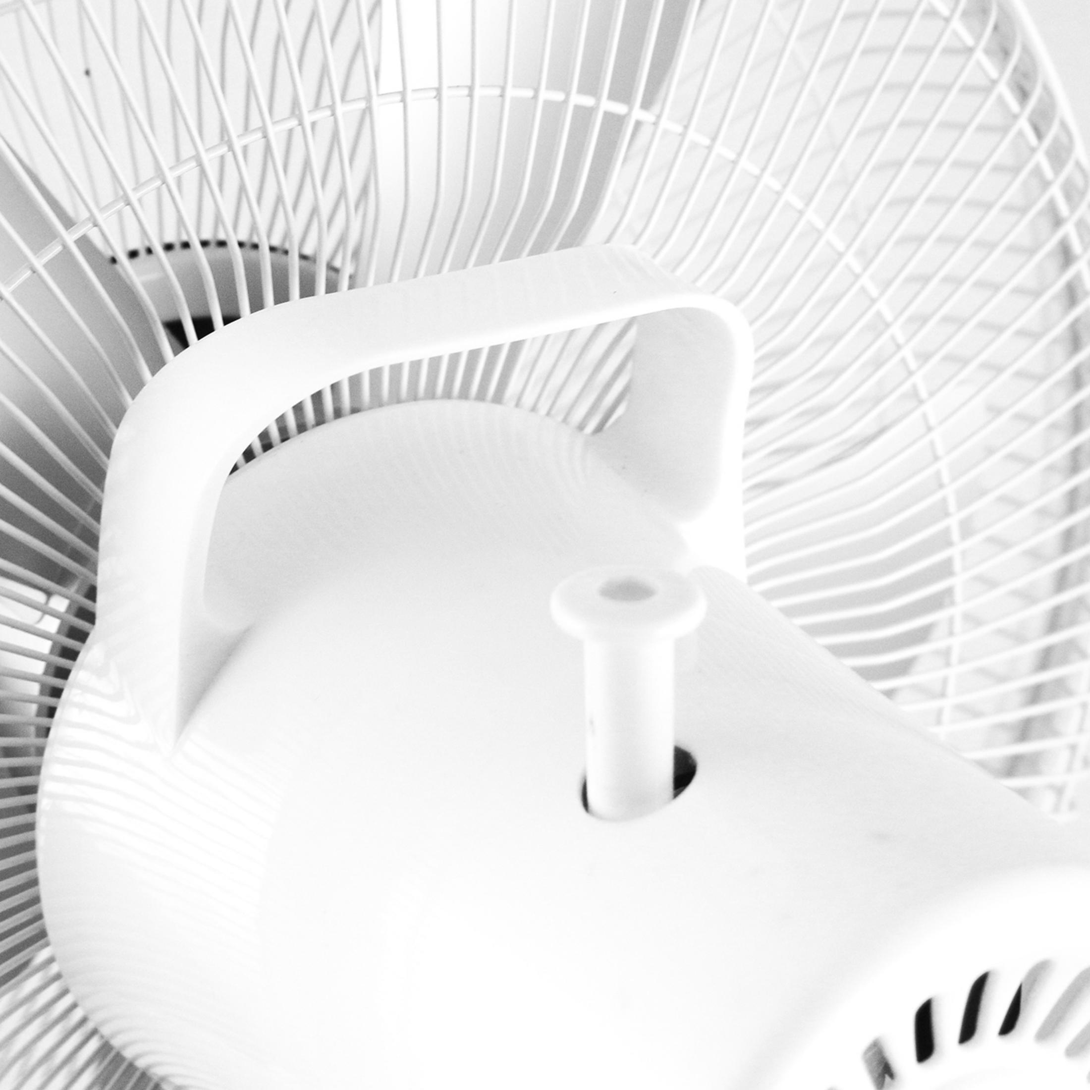 Un primo piano di un ventilatore bianco con una maniglia. La ventola è spenta e le pale sono visibili.