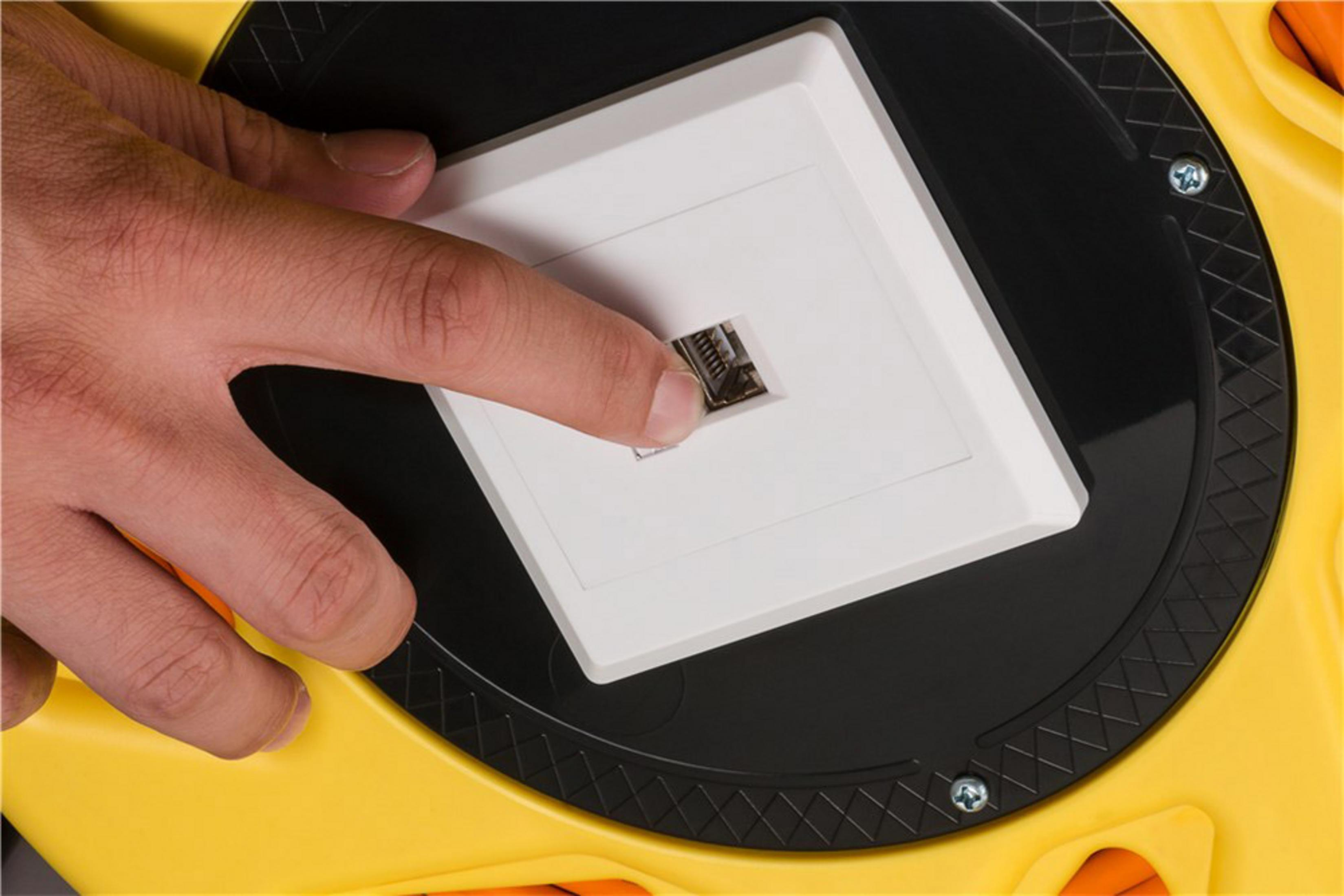 Ręka wkłada złącze RJ45 do białej płyty ściennej.