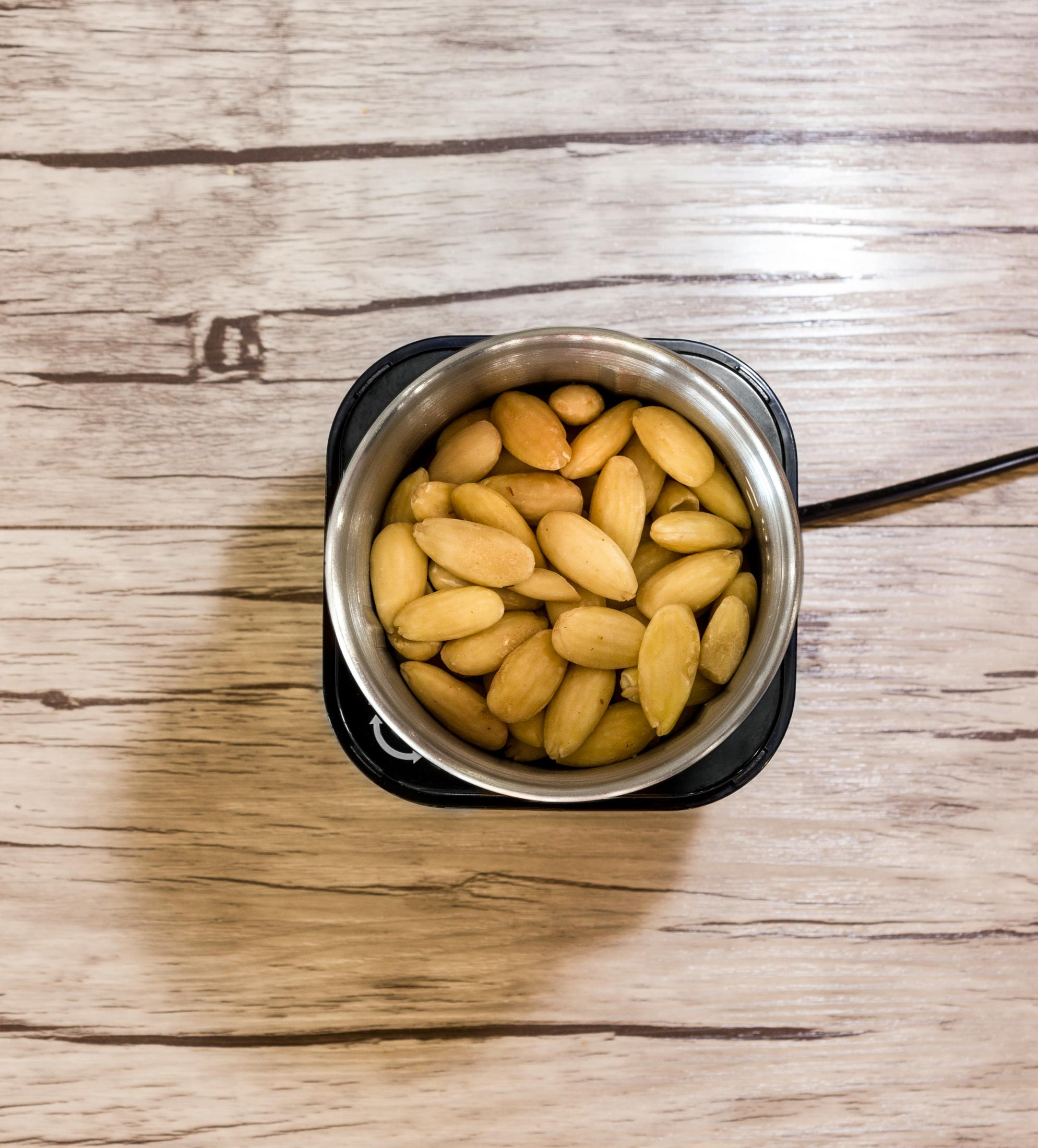 Widok z góry na migdały w stalowym garnku na drewnianym stole.