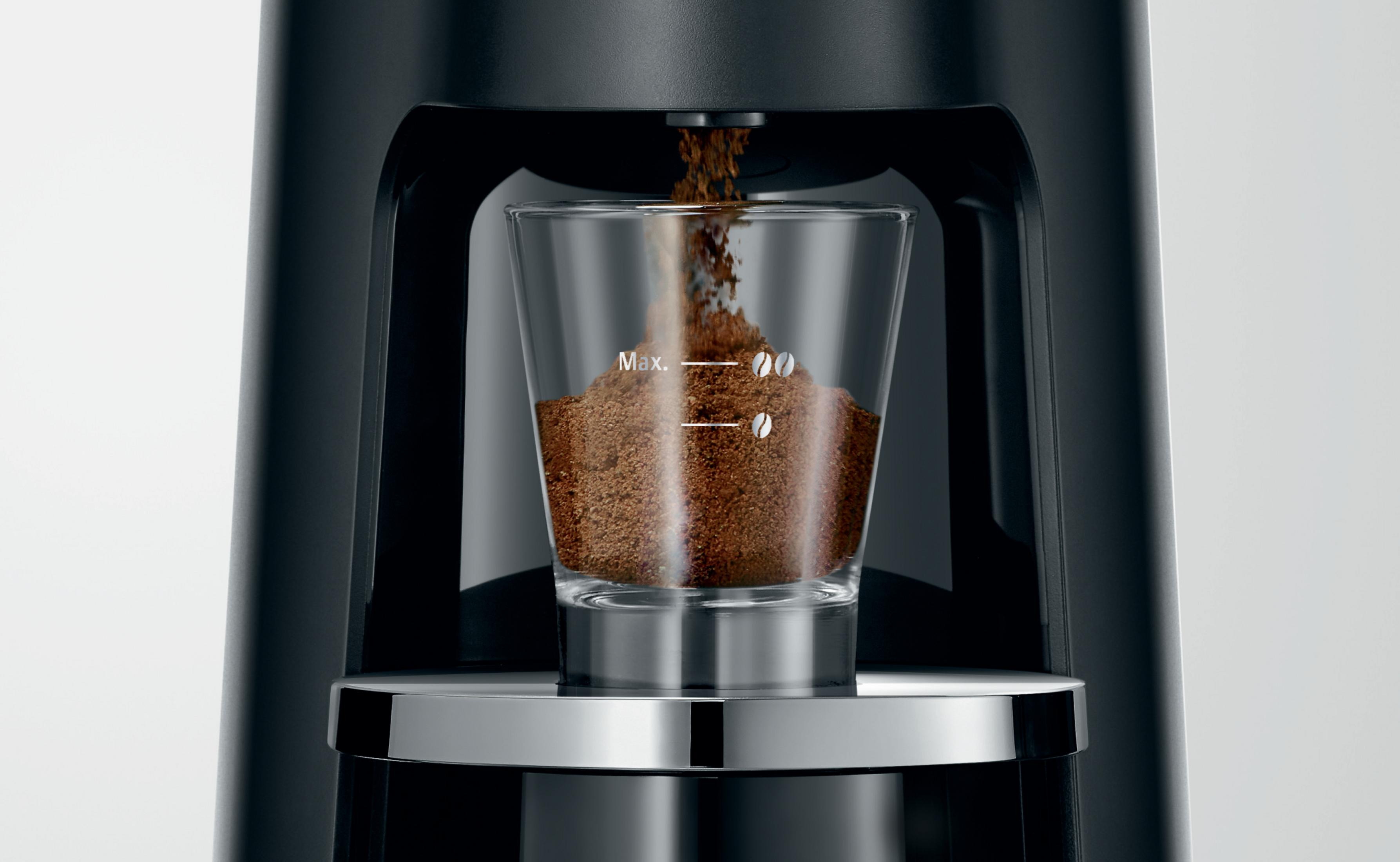 Kaffeemaschine mit gemahlenem Kaffee, der in eine Glas-Tasse gegossen wird, mit Füllständen.
