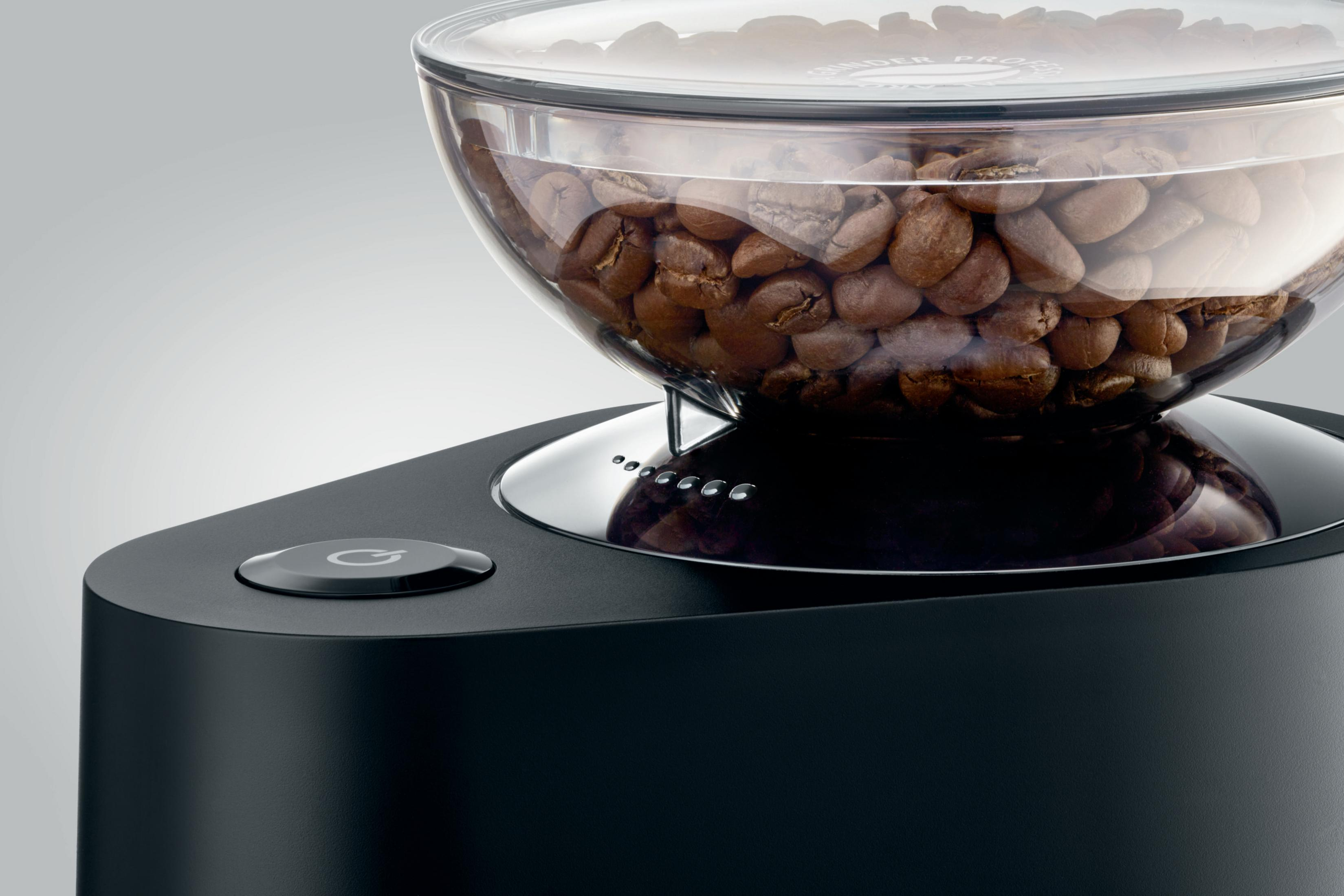 Nahaufnahme einer Kaffeemühle. Oben Kaffeebohnen. Schwarze Basis mit Ein-Aus-Taste.