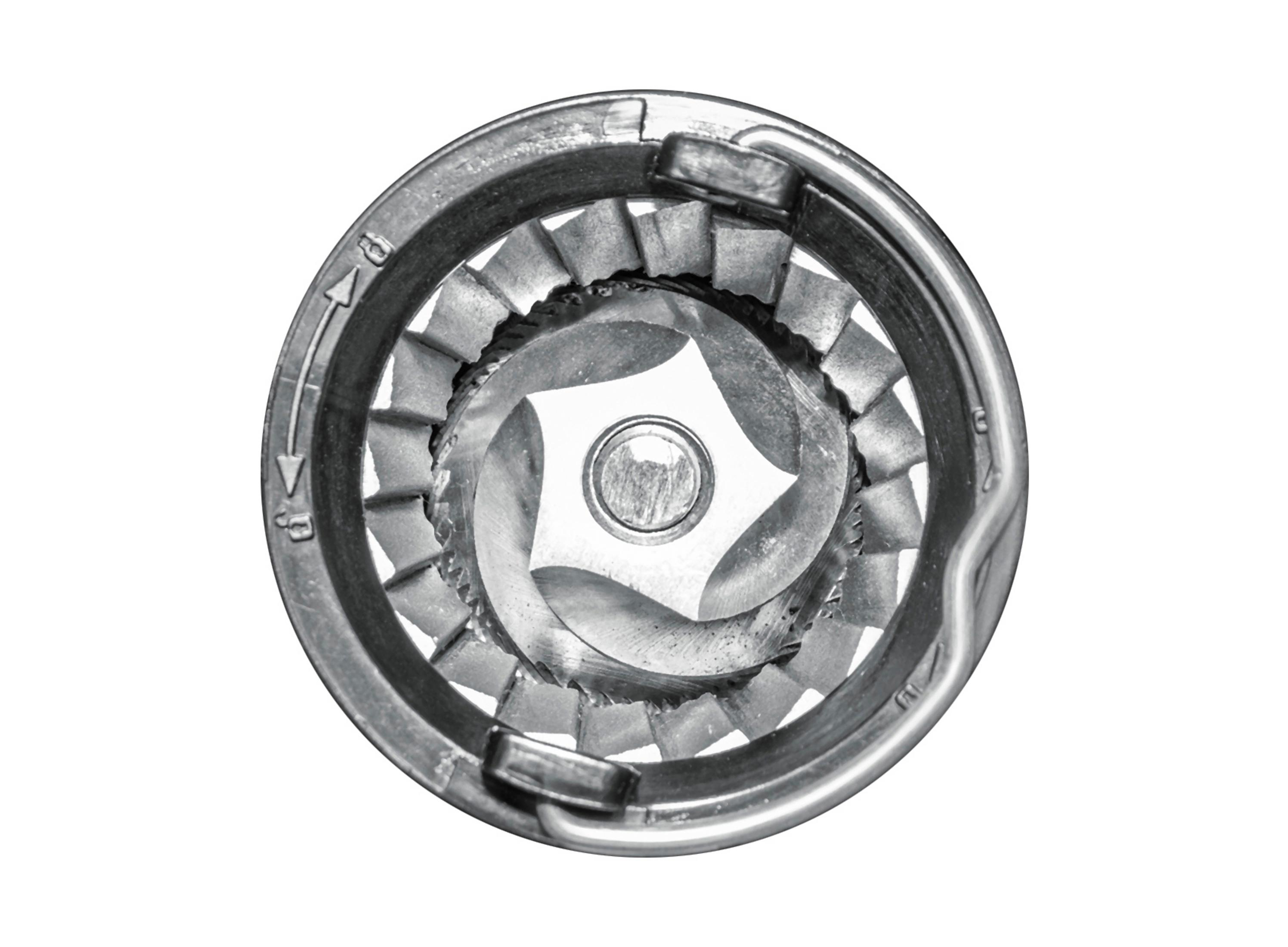 Zbliżenie mechanizmu młynka z metalowymi częściami. Ma ostrza i gwiaździsty środek ze strzałkami do regulacji.