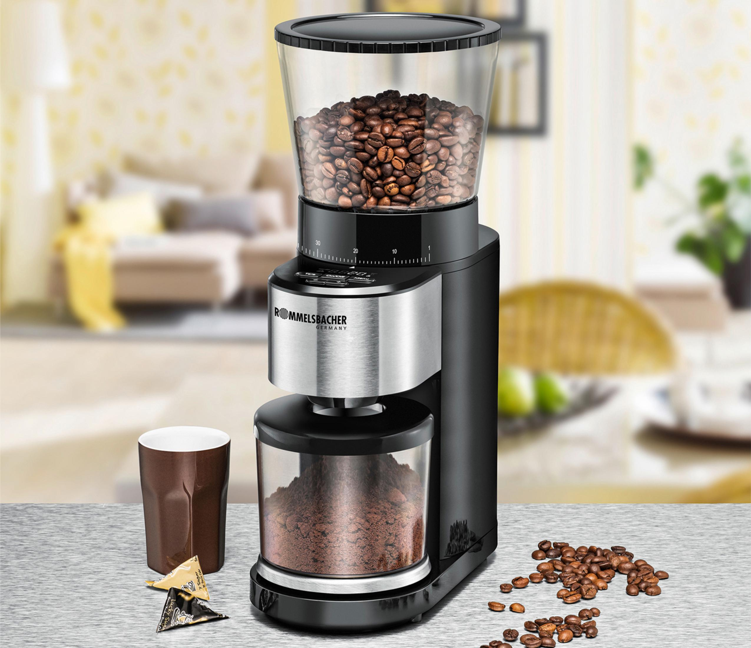 Czarny i srebrny młynek do kawy z ziarnami u góry i zmieloną kawą na dole.