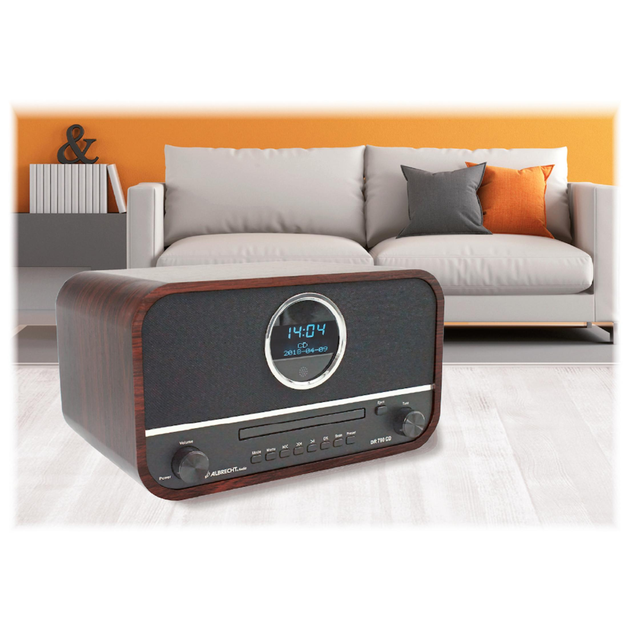 Radio in legno con display orologio digitale, sullo sfondo di un soggiorno.