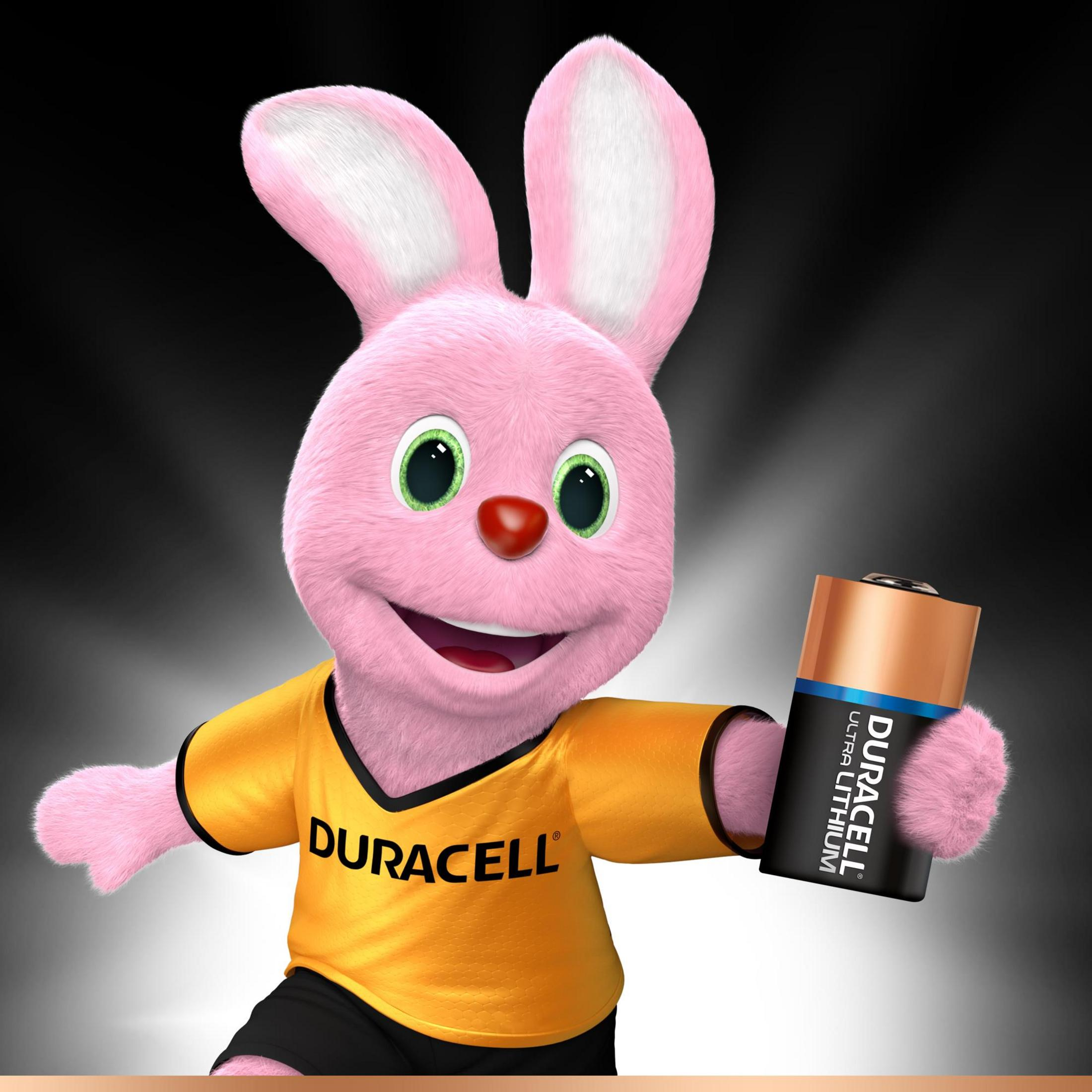 Królik Duracell trzymający baterię Duracell, ubrany w żółtą koszulkę Duracell.