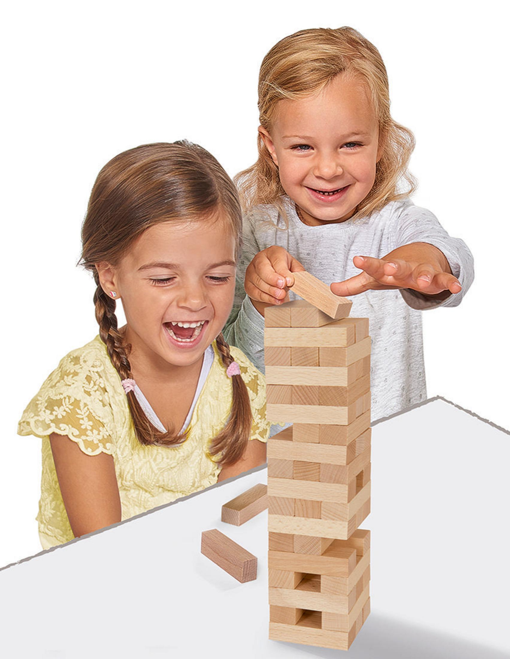 Zwei Mädchen spielen Jenga. Ein Mädchen legt einen Block, das andere schaut zu und lächelt.