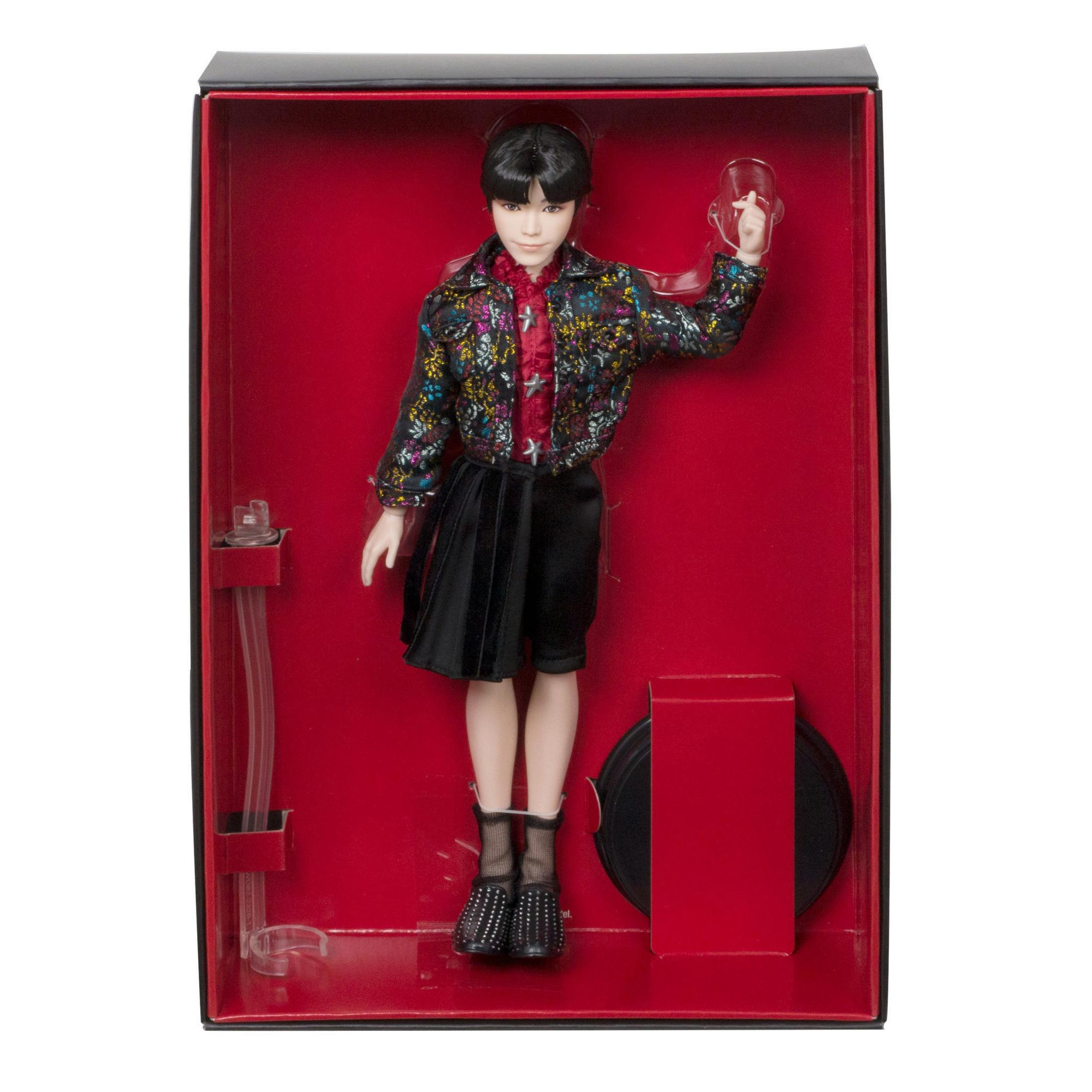 Puppe in einer Box, junger Mann in Jacke und Rock.