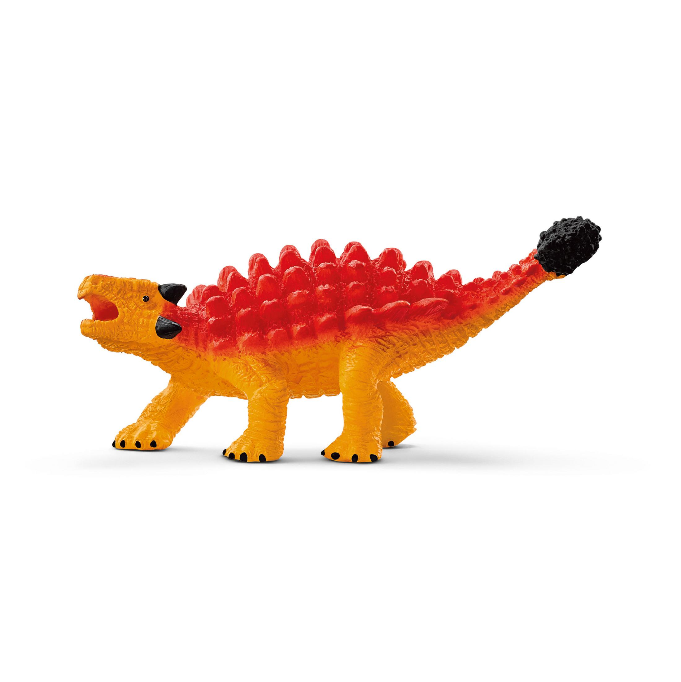 Un dinosaure jouet orange et jaune avec un dos épineux et une pointe de queue noire. Sur une surface blanche.