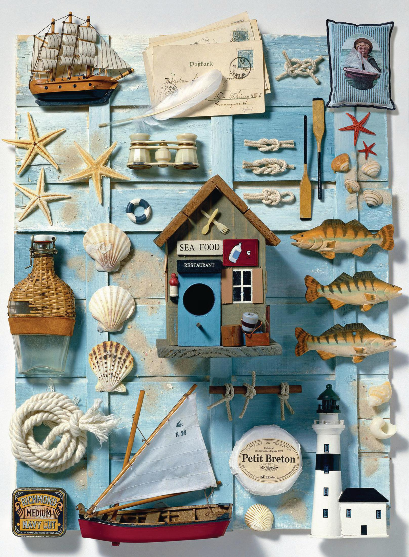 Wyświetlacz o tematyce nadmorskiej z miniaturową łodzią, latarnią morską, muszlami i innymi przedmiotami.