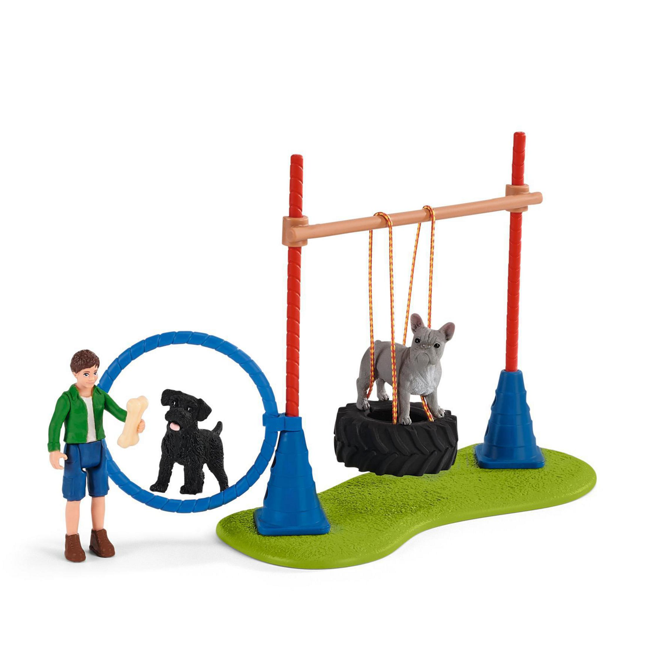 Figuren eines Jungen und Hunde beim Agility-Training. Es gibt Hindernisse und Ausrüstung.
