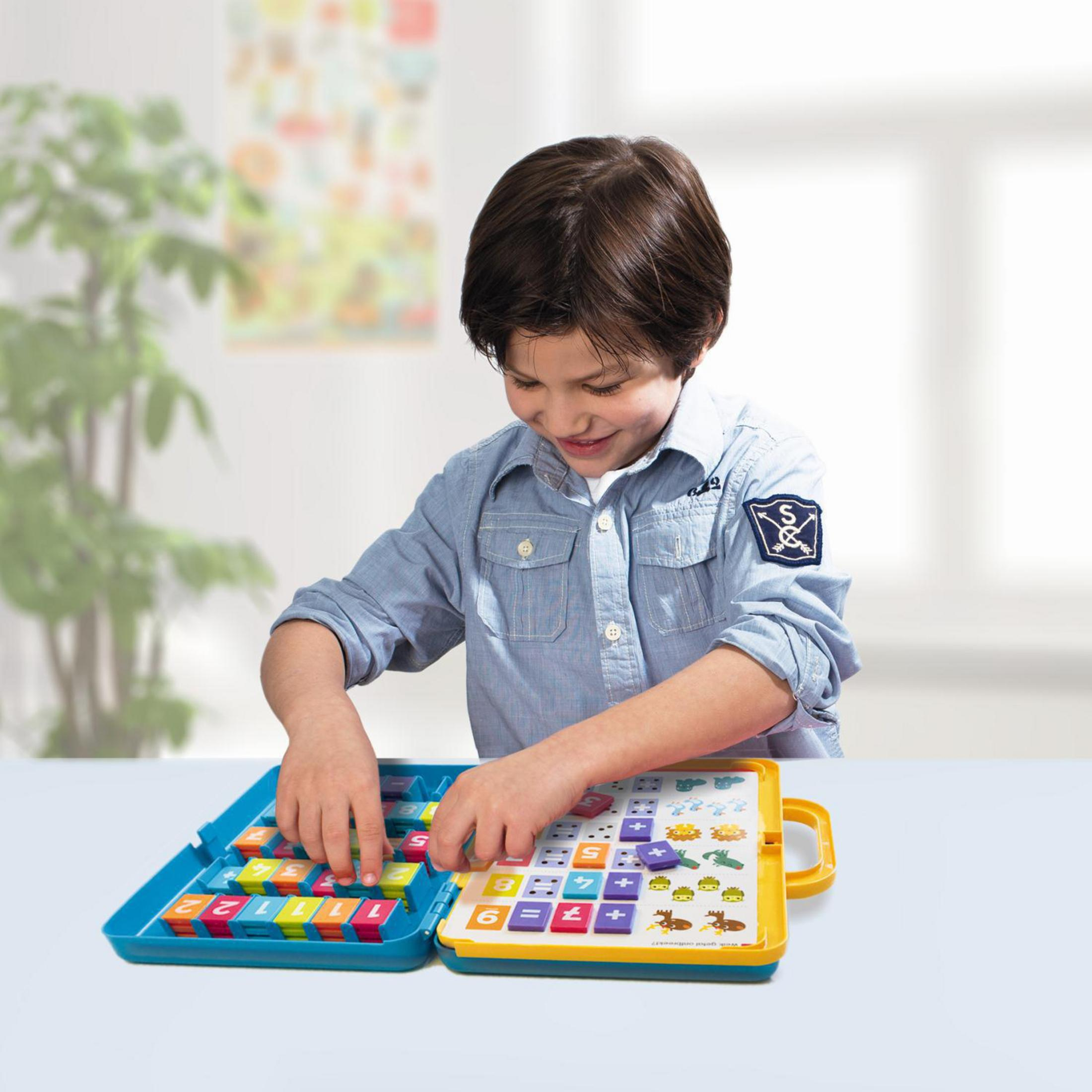 Ein Junge spielt mit einem Spielzeug. Das Spielzeug hat bunte Blöcke mit Zahlen und Symbolen.