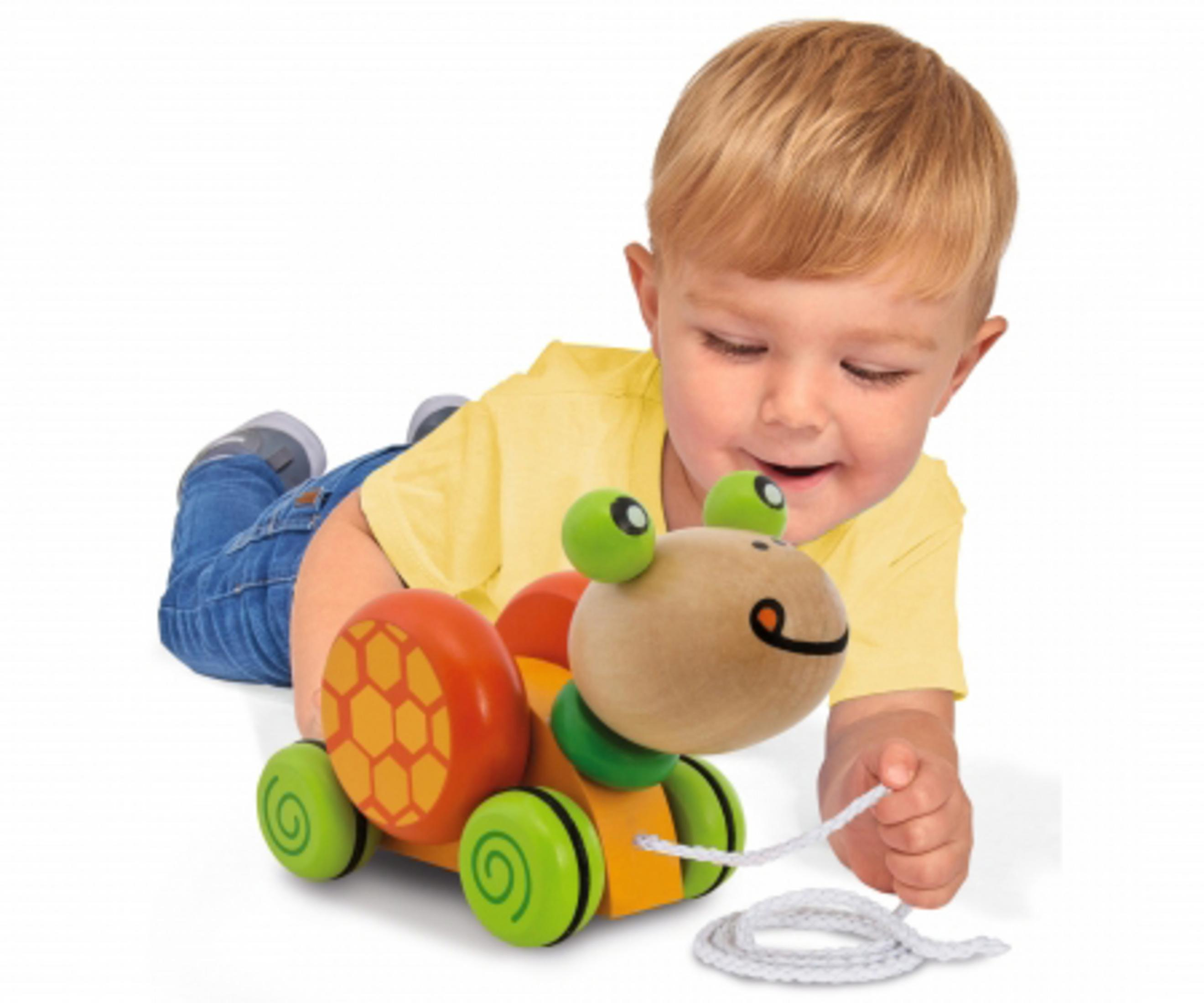 Ein Baby spielt mit einem Holzschneckenspielzeug. Die Schnecke hat ein rotes Gehäuse, einen orangefarbenen Körper.