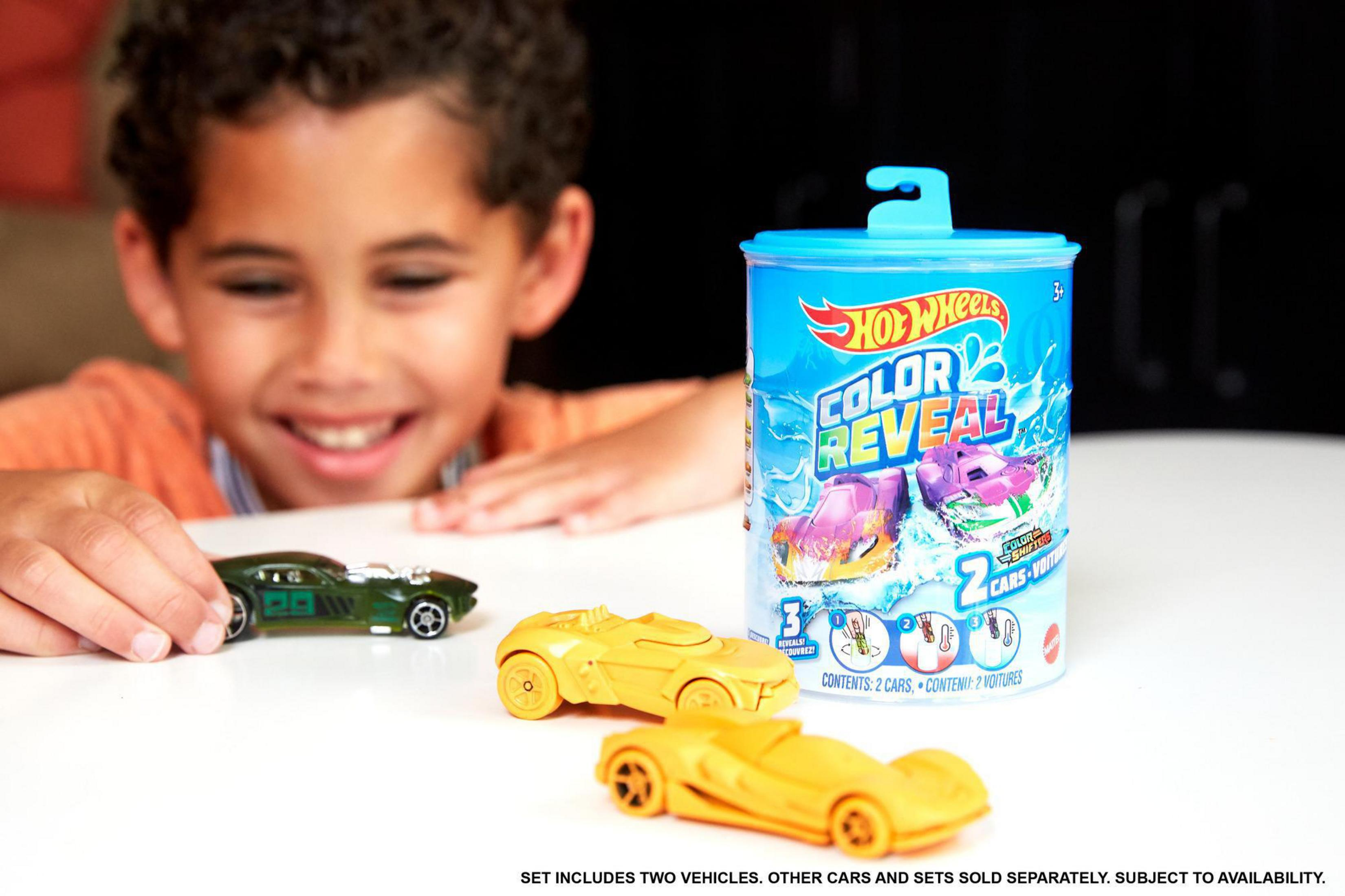 Uśmiechnięty chłopiec z samochodzikami i puszką samochodzików Hot Wheels Color Reveal.
