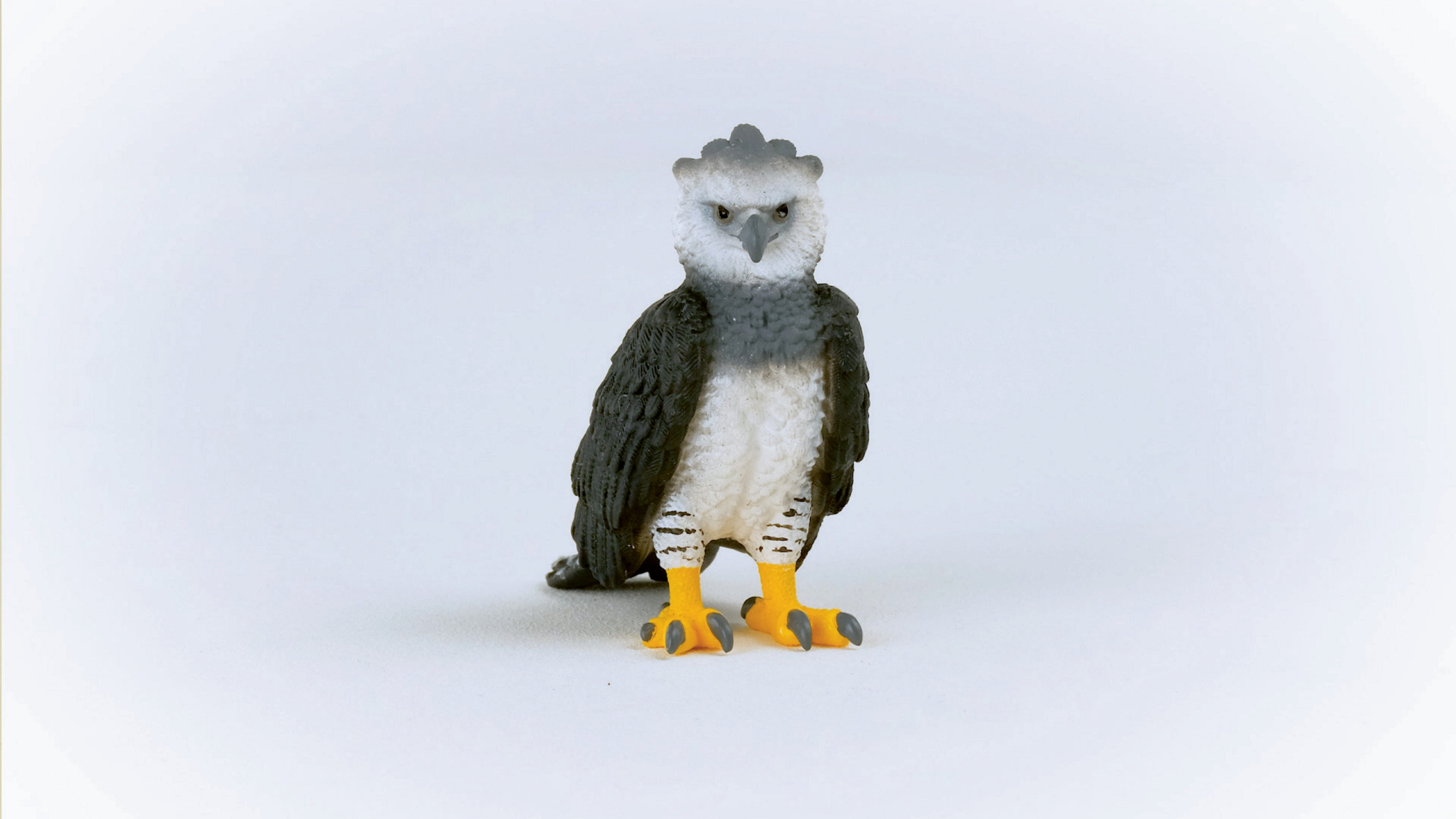 Zabawkowa figurka orła harpii na białym tle, zwrócona przodem.