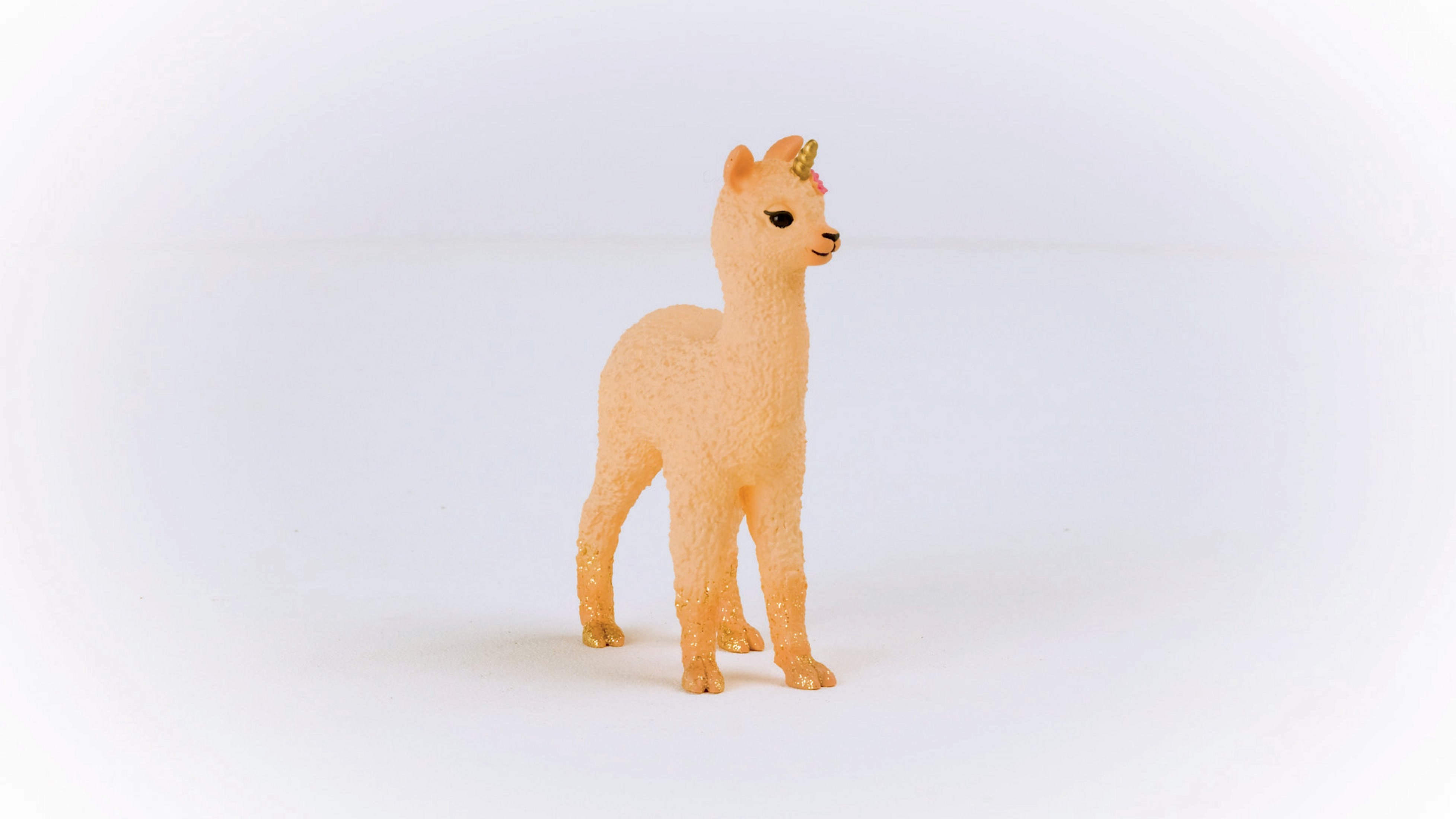 Un giocattolo a forma di lama con un corno di unicorno su una superficie bianca. Dettagli dorati sugli zoccoli.