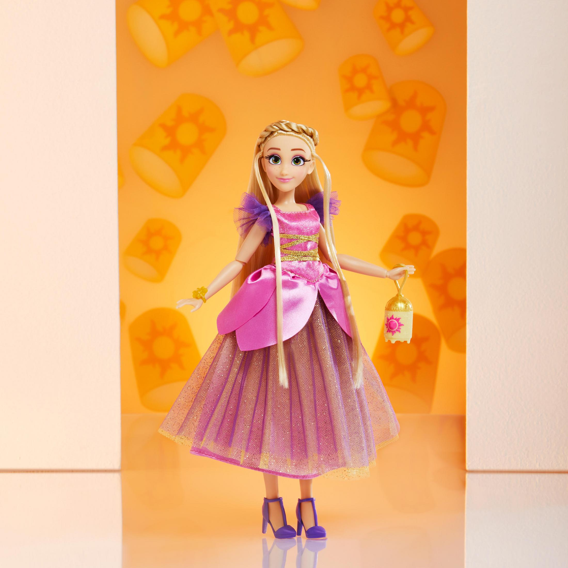 Tangled-Puppe mit langen blonden Haaren, rosa Kleid, Laterne haltend, vor gelbem Laternenhintergrund.