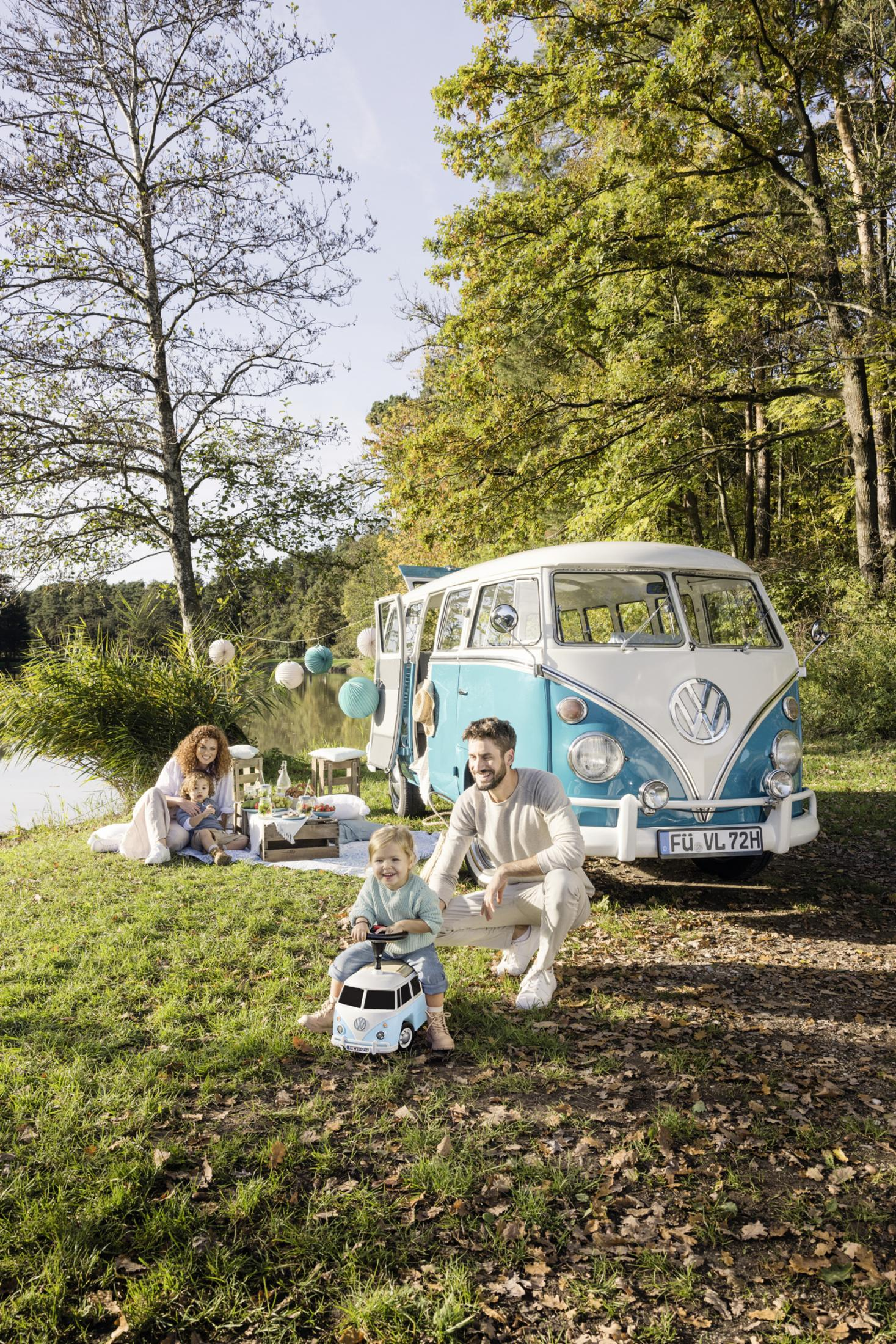 Familienpicknick mit einem Oldtimer-VW-Bus. Ein Kind sitzt auf einem Spielzeugauto.